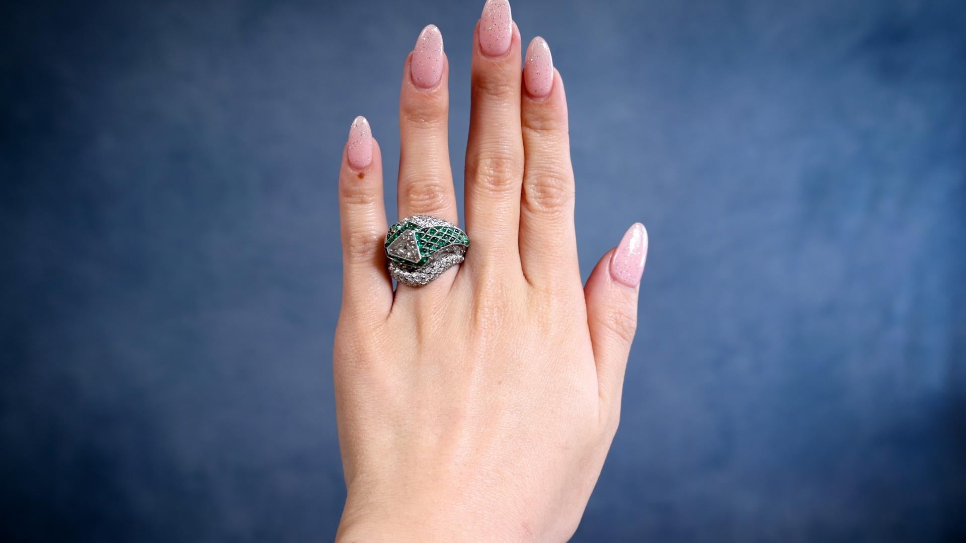 One Art Deco Inspired Diamond and Emerald Platinum Snake Ring. Featuring one triangular cut diamond of 1.16 carats, graded K color, SI1 clarity. Accented by 184 old European cut diamonds with a total weight of approximately 1.75 carats, graded