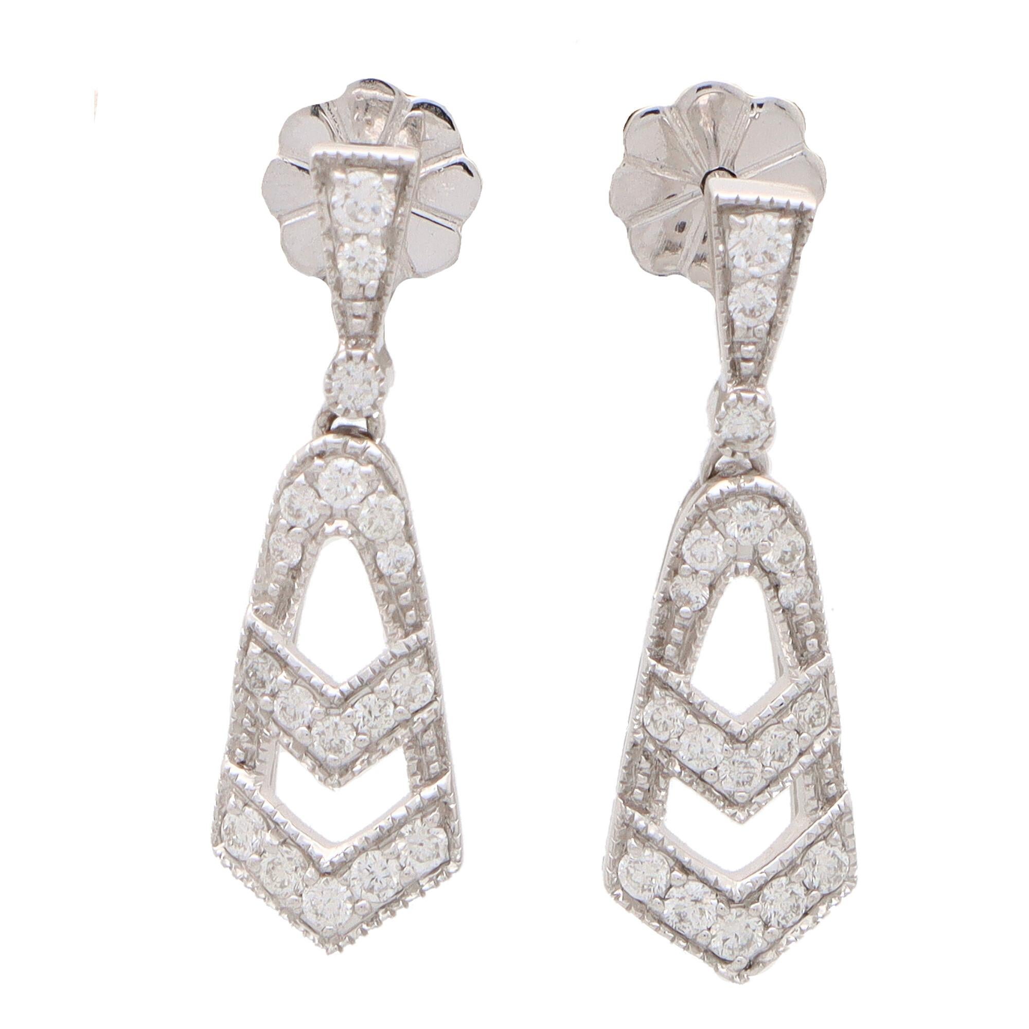  A beautiful pair of Art Deco inspired diamond drop earrings set in 18k white gold.

Echoing that of the Art Deco era, each earring is composed of an openwork diamond drop. The drop hangs from a matching diamond set bail and the earrings are secured