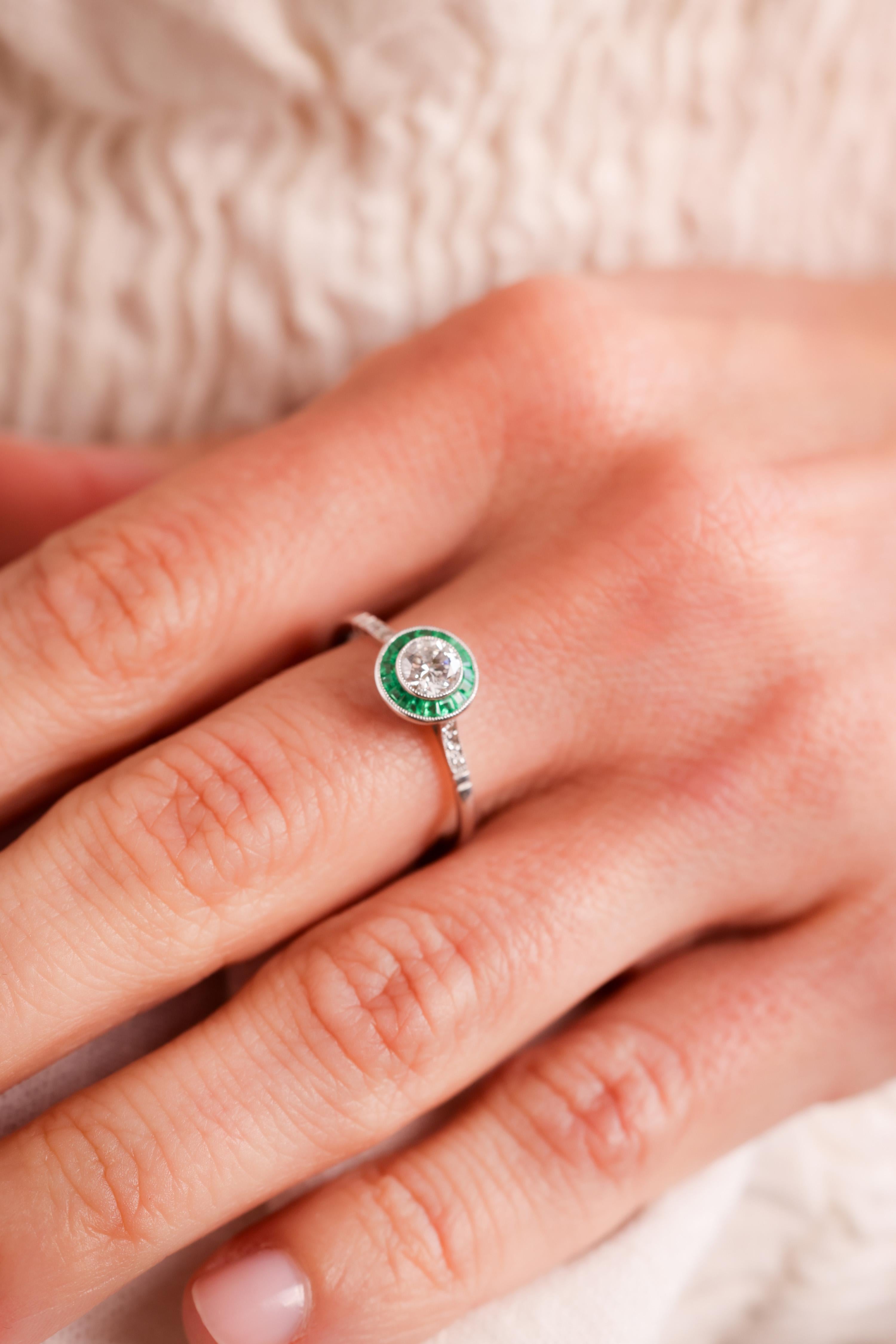 Center Stone: Diamond
Cut: Old European Cut
Weight: 0.37 Carats
Color: F
Clarity: SI
Accent Stone: 17 Emeralds
Cut: Calibre Cut
Weight: Approximately .6 Carats
Color: Green
Accent Stone: 6 Diamonds
Cut: Rose Cuts
Weight: Approximately 0.02