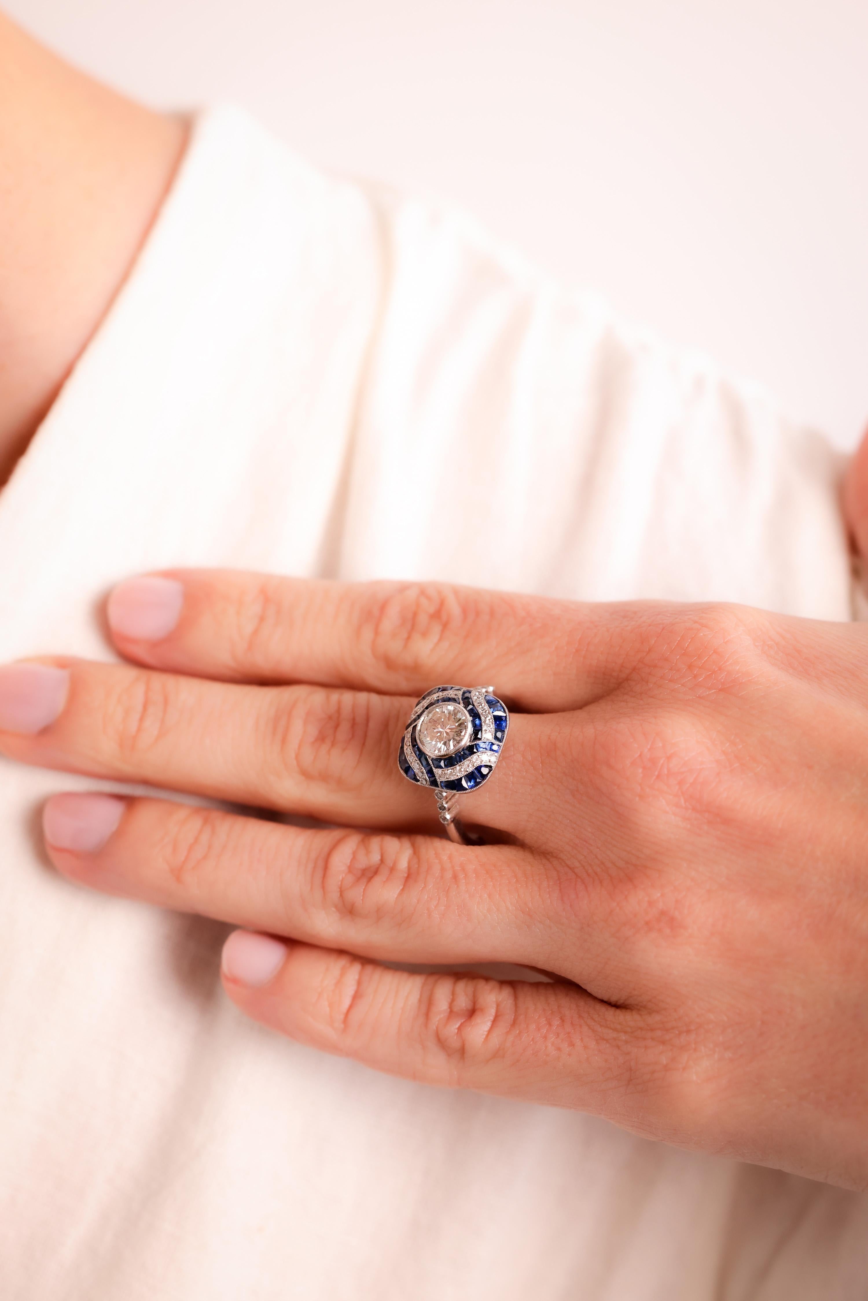 Center Stone: Diamond
Cut: Round Brilliant Cut
Weight: 0.97 Carat
Color: J
Clarity: SI
Accent Stone: 40 Sapphires
Cut: Calibre Cut
Weight: Approximately 0.5 Carats
Color: Blue
Accent Stone: 34 Diamonds
Cut: Old European and Round Brilliant