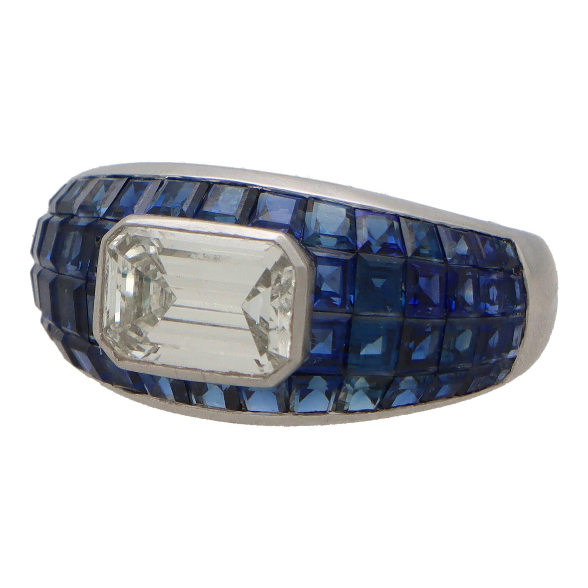 A beautiful Art Deco inspired blue sapphire and diamond bombe dress ring set in platinum.

The ring is composed in a striking bombe design, invisibly set with calibre cut blue sapphire stones. Set centrally to the ring is a rub over set emerald cut