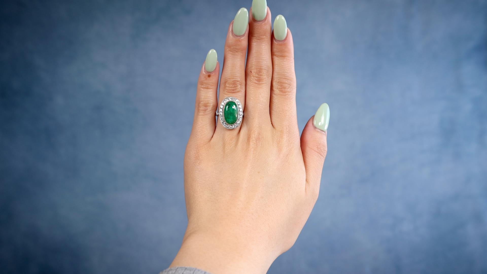Ein Art Deco inspirierter Smaragd-Diamant-Platin-Ring. Mit einem Smaragd im Cabochon-Schliff mit einem Gewicht von etwa 3.90 Karat. Akzentuiert durch 30 runde Diamanten im Brillantschliff mit einem Gesamtgewicht von ca. 0,75 Karat, eingestuft in