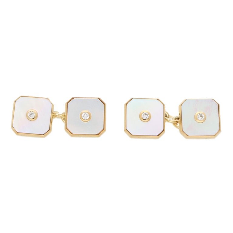A beautiful pair of Art Deco inspired mother of pearl and diamond chain link cufflinks set in 9k yellow gold.

Each cufflink is composed of two square faces set centrally with a bezel set round brilliant cut diamond. The diamond twinkles elegantly