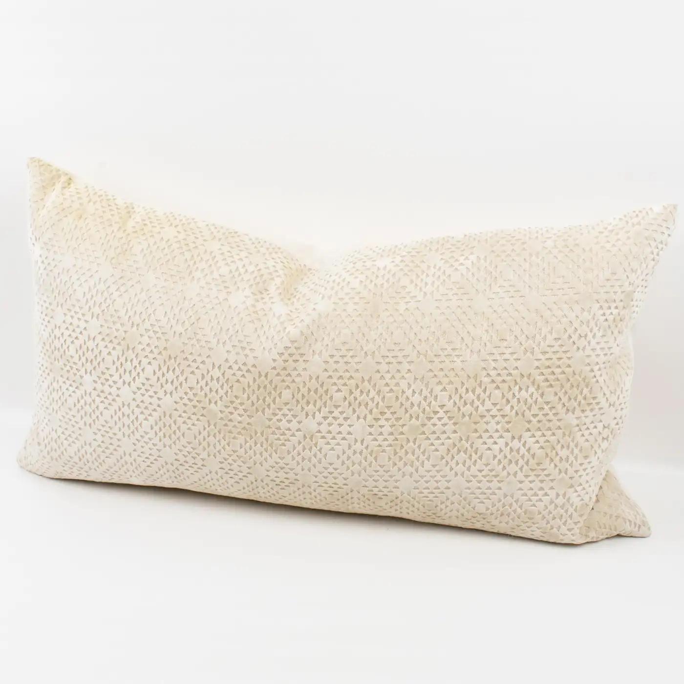This lovely Art Deco-inspired velvet throw pillow features a lumbar-shaped pillow, covered on the front with a textured geometric design in off-white velvet. The back is made of the same colored velvet with a plain design. A zipper encloses an inner