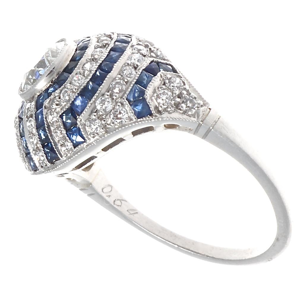 This vibrant ring pays homage to the Jazz age in the most beautiful way and designed in the Art Deco style. Featuring a sparkling old European cut diamond that is just over 0.50 carats. Surrounding the fiery facets are rows of more old European cut
