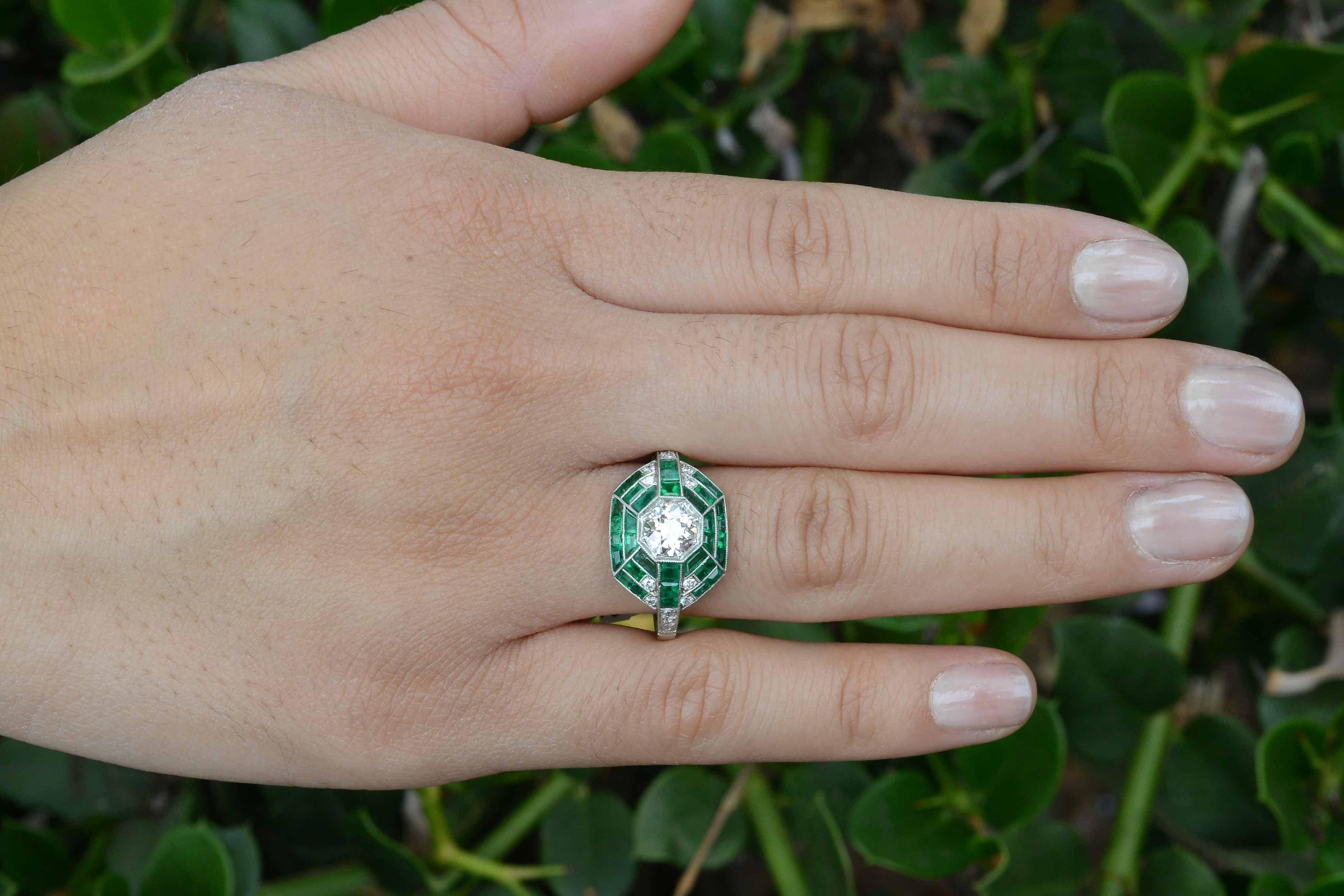 With a design inspired by the Art Deco era, a master jeweler revived this antique diamond and emerald masterpiece from the band on up to it's current glory. Centering on a fiery, old European brilliant weighing 0.80 carat (graded as H color VS1