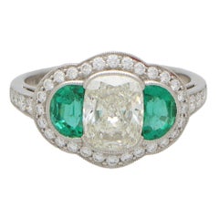 Art Deco Inspired Oval Diamond and Emerald Haloed Three Stone Ring in Platinum
