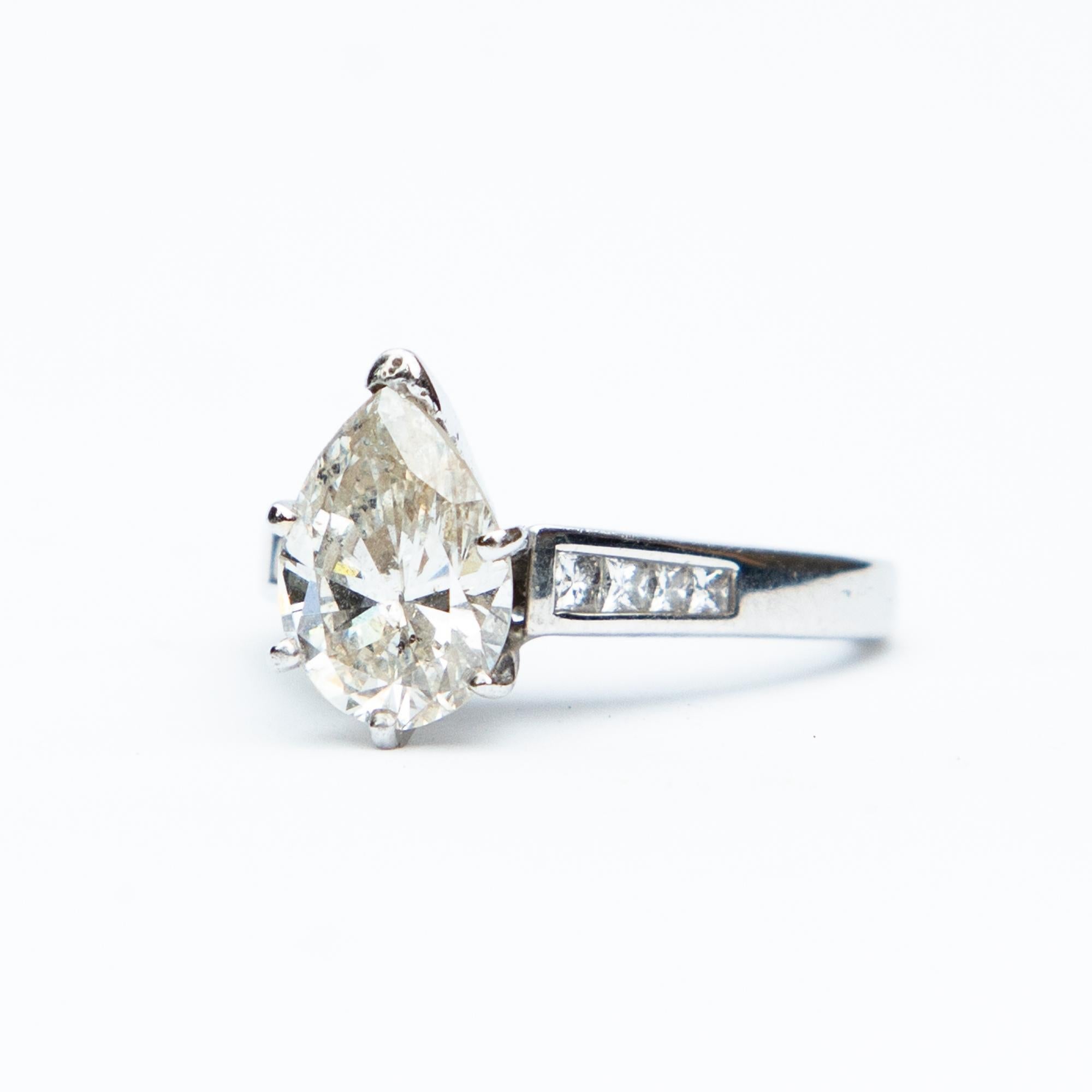 This a sensational Art Deco inspired  pear cut solitaire platinum and diamond ring. The central Diamond measures an 1 carat 32, beautifully set in a raised fourteen carat white gold setting with princess cut diamond shoulders. Total diamond weight