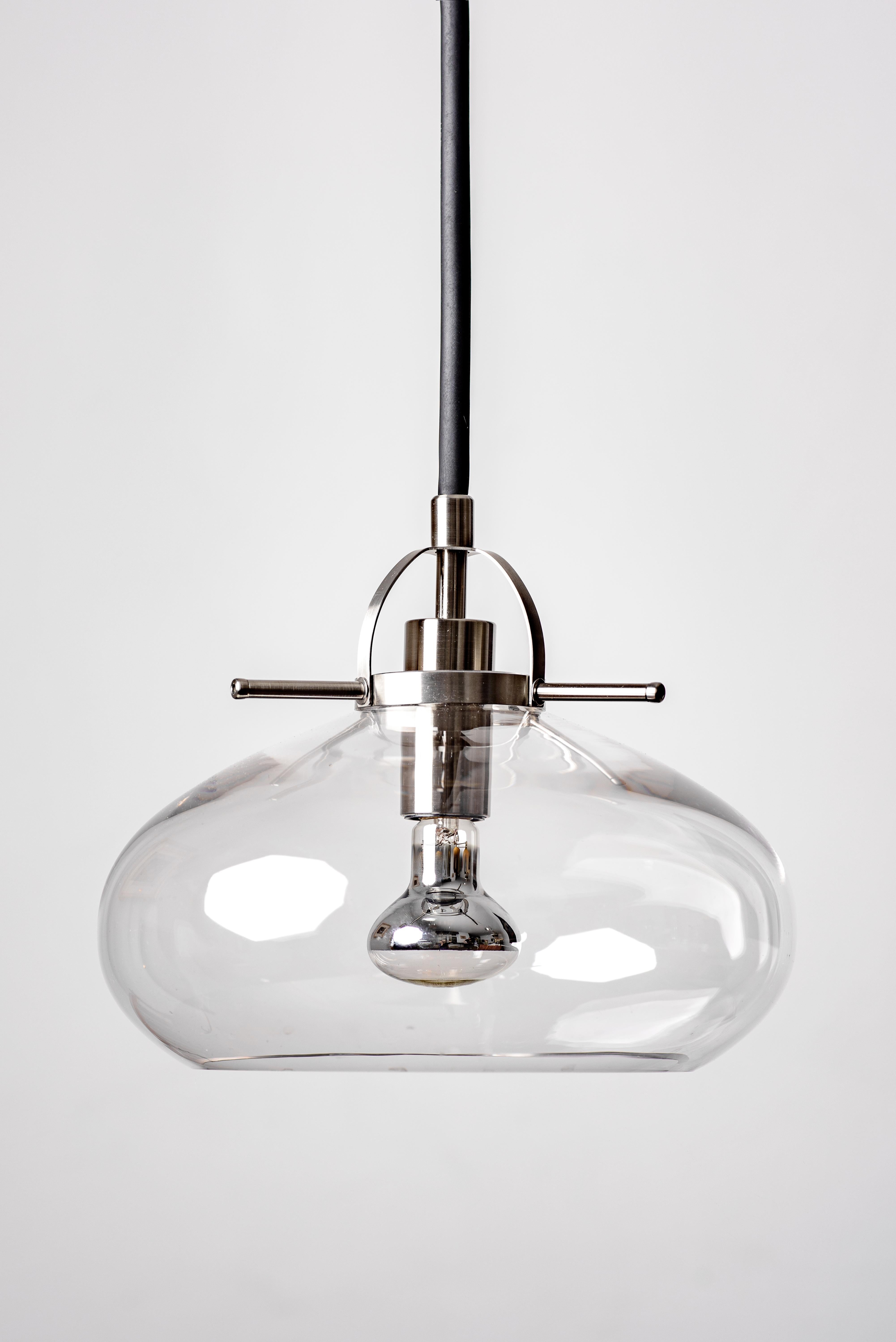 Art Deco-inspired pendant lamps are available in three unique versions, each with its own distinct look and feel. Crafted from the finest quality materials, this lamp features sleek stainless steel elements and a beautiful clear glass shade that