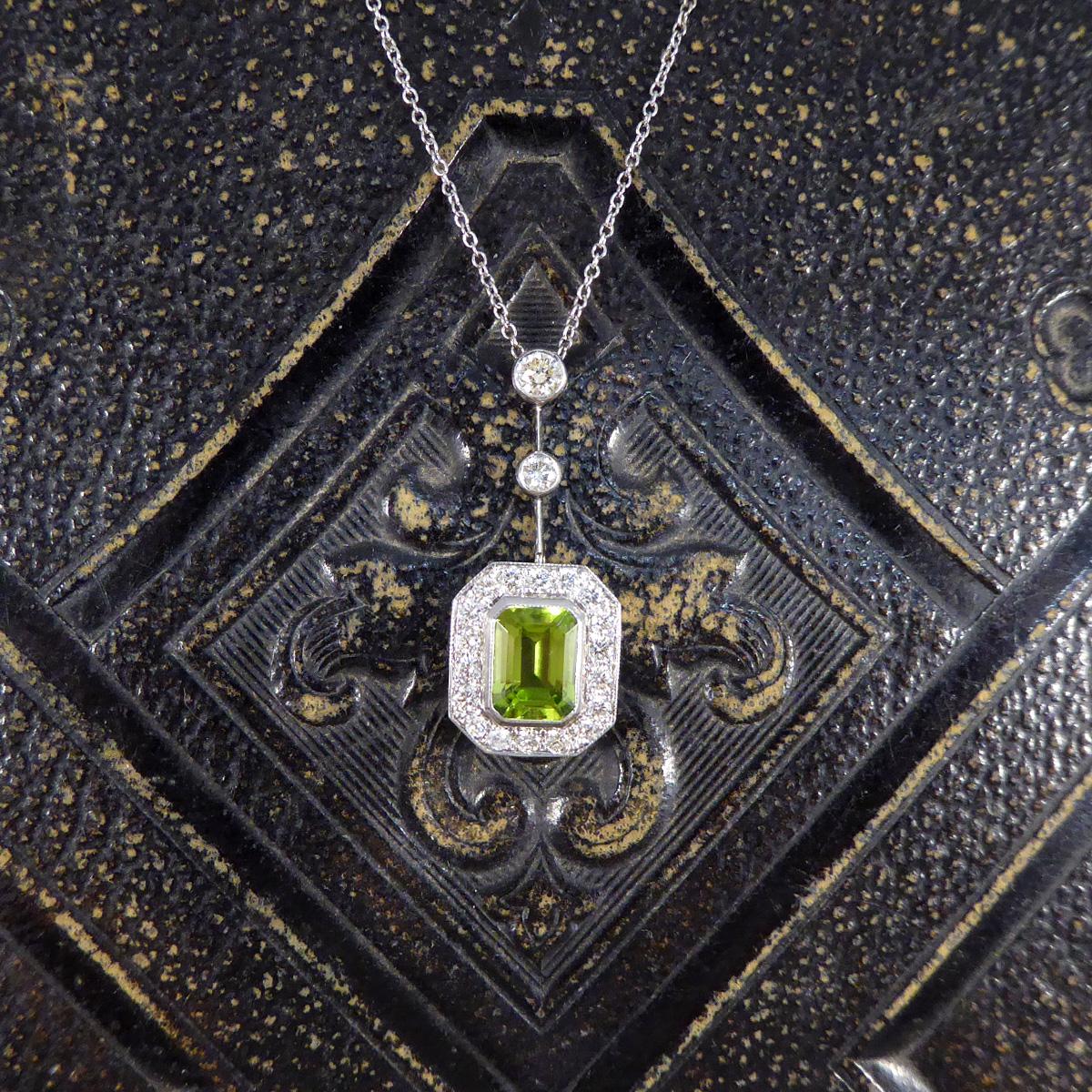 This beautiful contemporary necklace has been hand crafted from 18ct White Gold in an Art Deco style. It features an Emerald Cut Peridot in a slight millegrain edge setting weighing 2.25ct with a surround of 18 Diamonds, making it hold a total of