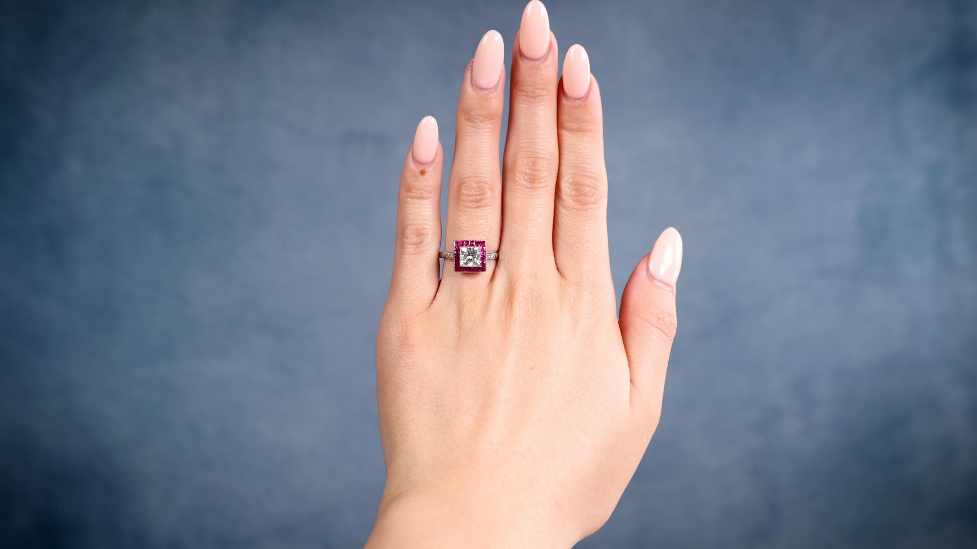 One Art Deco Inspired Princess Cut Diamond Ruby Platinum Target Ring. Featuring one princess cut diamond weighing approximately 1.15 carats, graded J color, VS1 clarity. Accented by 20 French cut rubies with a total weight of approximately 0.80