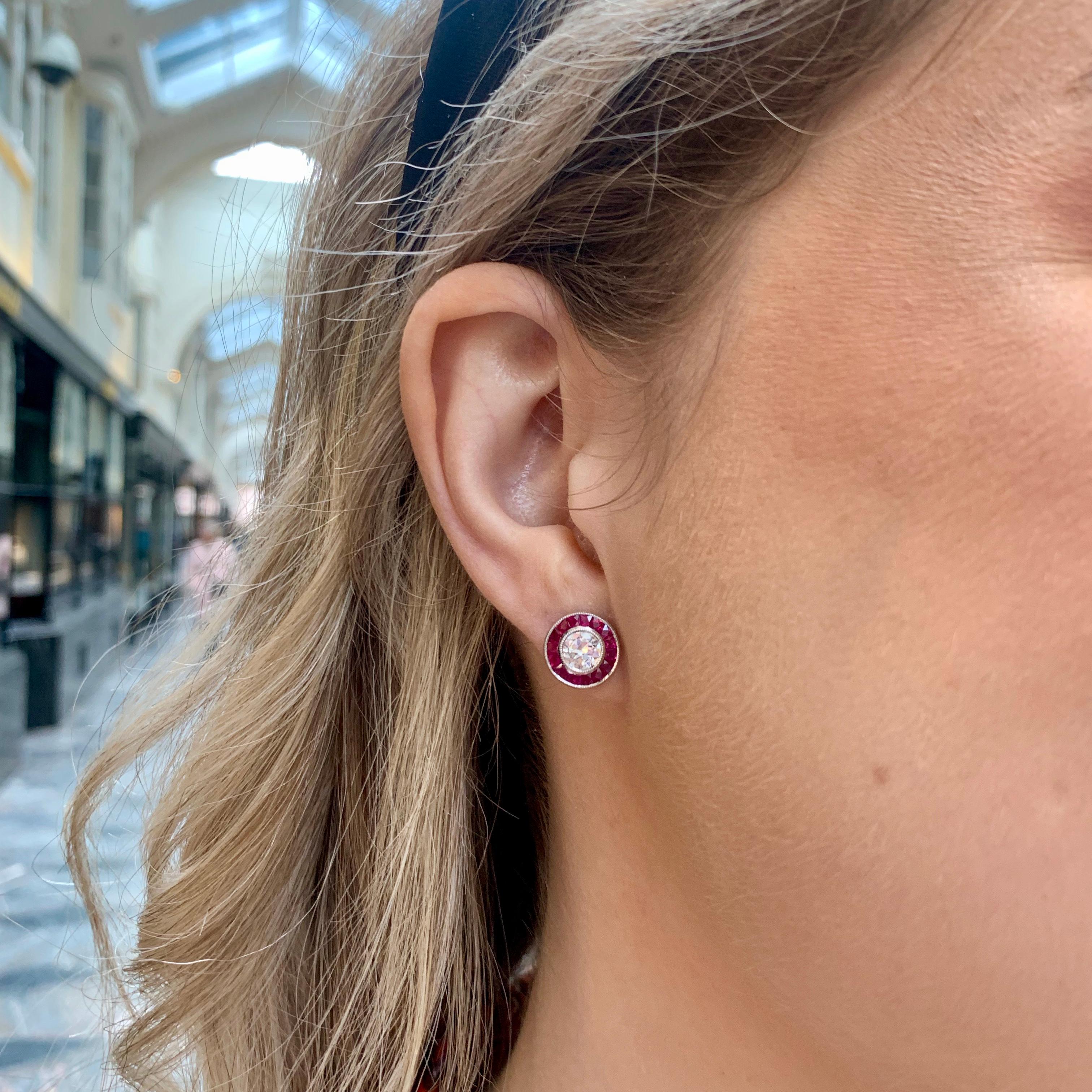  A beautiful pair of Art Deco style diamond and ruby target earrings set in platinum.

Each earring is predominantly set with a sparkly 0.51 carat round cut diamond which is rub over set to centre. Each diamond is then elegantly surrounded by a