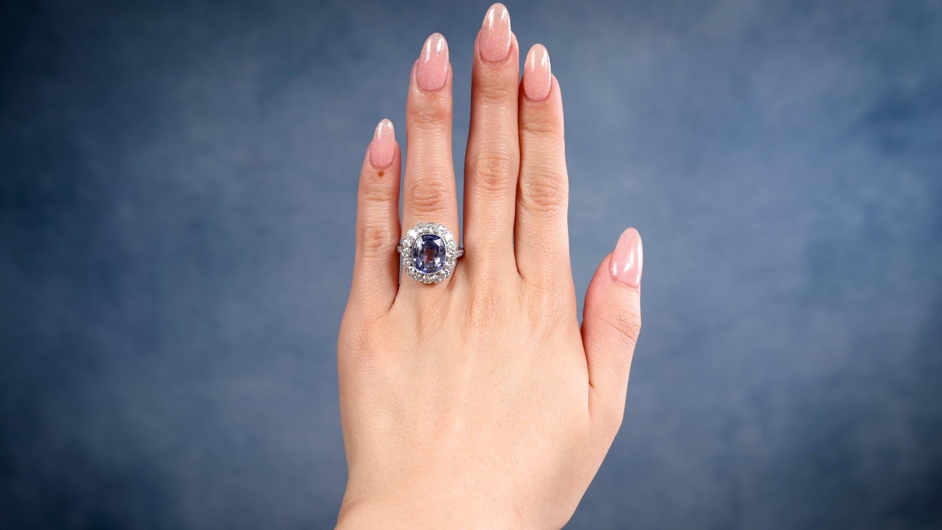 One Art Deco Inspired Sapphire and Diamond Platinum Ring. Featuring one cushion cut sapphire weighing approximately 6.00 carats. Accented by 22 round brilliant cut diamonds with a total weight of approximately 1.40 carats, graded near-colorless, VS