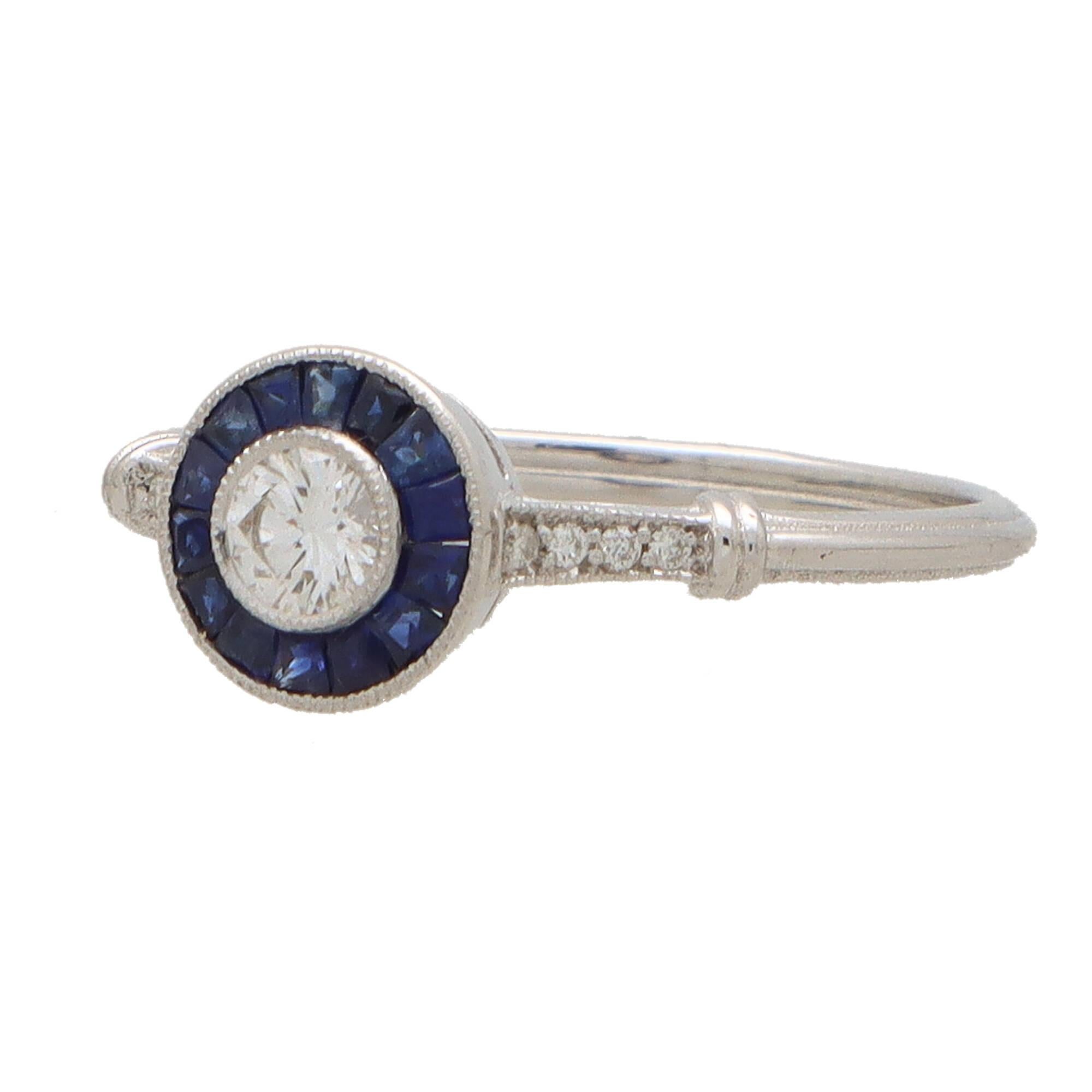 A beautiful Art Deco inspired diamond and sapphire ring set in 18k white gold.

This elegant ring is centrally set with a sparkly round brilliant cut diamond which is millegrain set. The diamond is then surrounded by a target of calibre cut blue