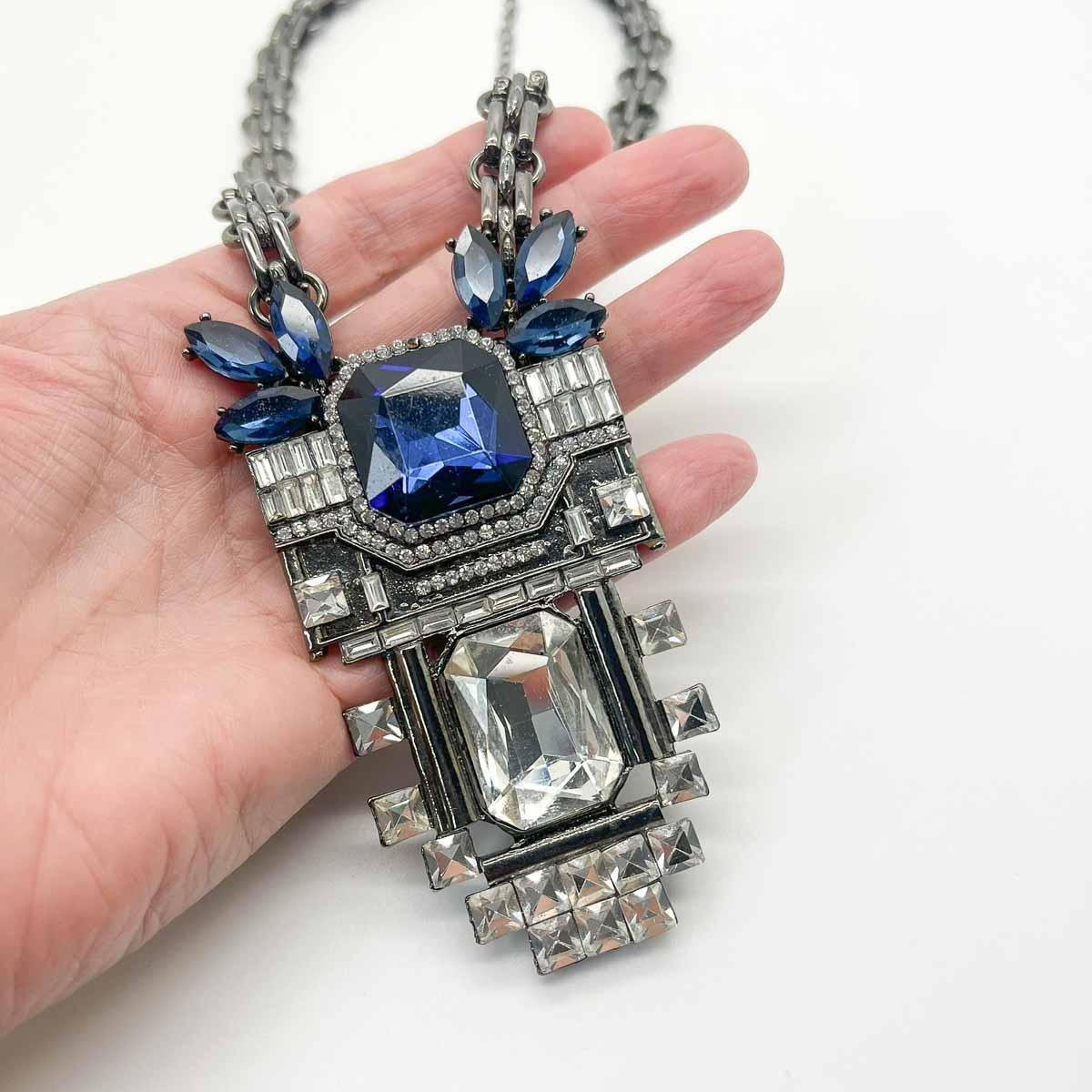 Un favoloso bavaglino di cristallo Art Déco. Ispirato al meglio del design Art Deco e sovradimensionato per ottenere il massimo impatto. Enormi cristalli di vetro bianchi e blu circondati da una miriade di pietre tagliate a fantasia assicurano