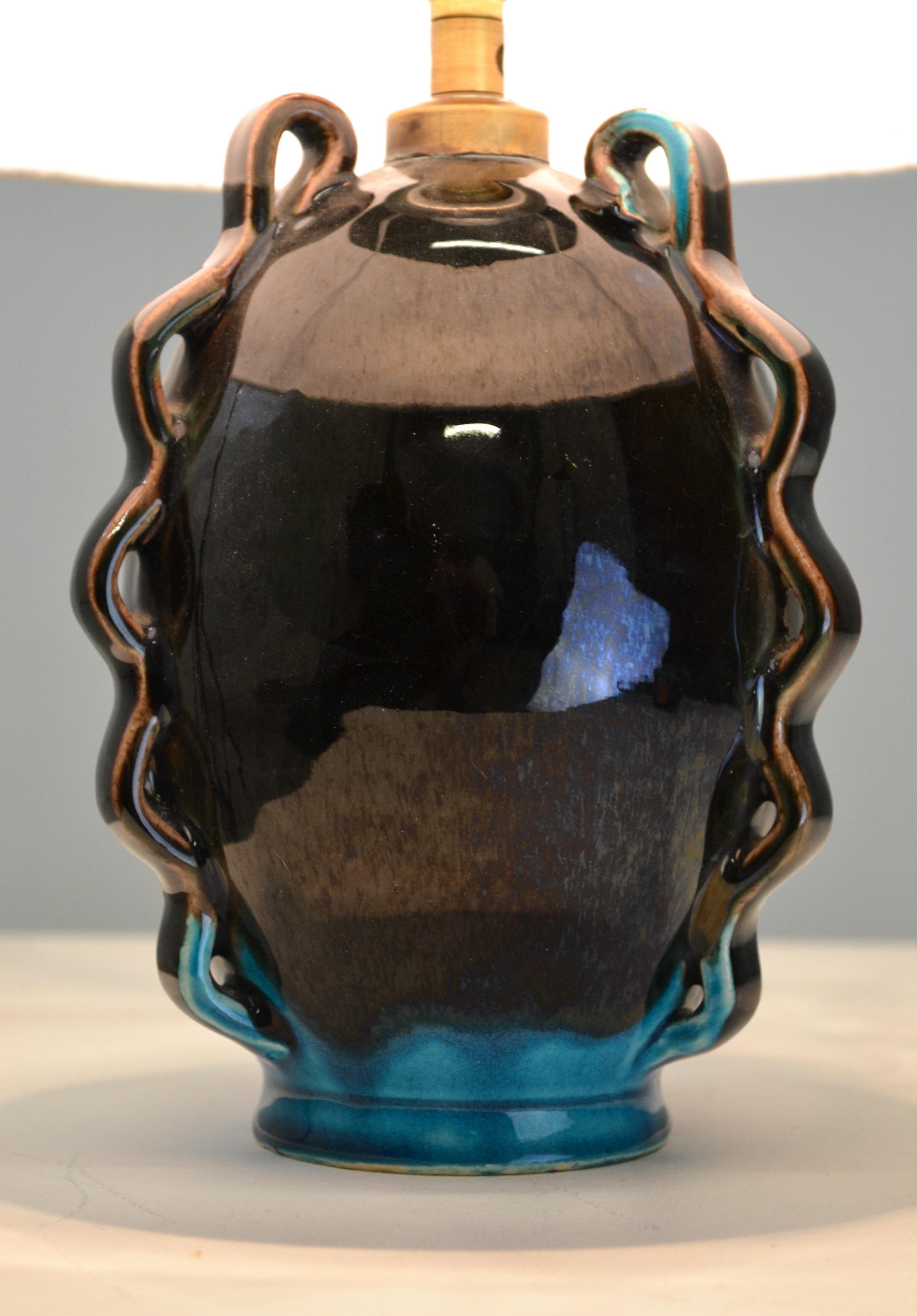 Rara lámpara de sobremesa de cerámica del renombrado Potiers d'Accolay, con un llamativo acabado de esmalte negro con vidriado azul y motivos geométricos que recuerdan el estilo Art Déco.

En excelente estado, esta pieza está firmada y estampada