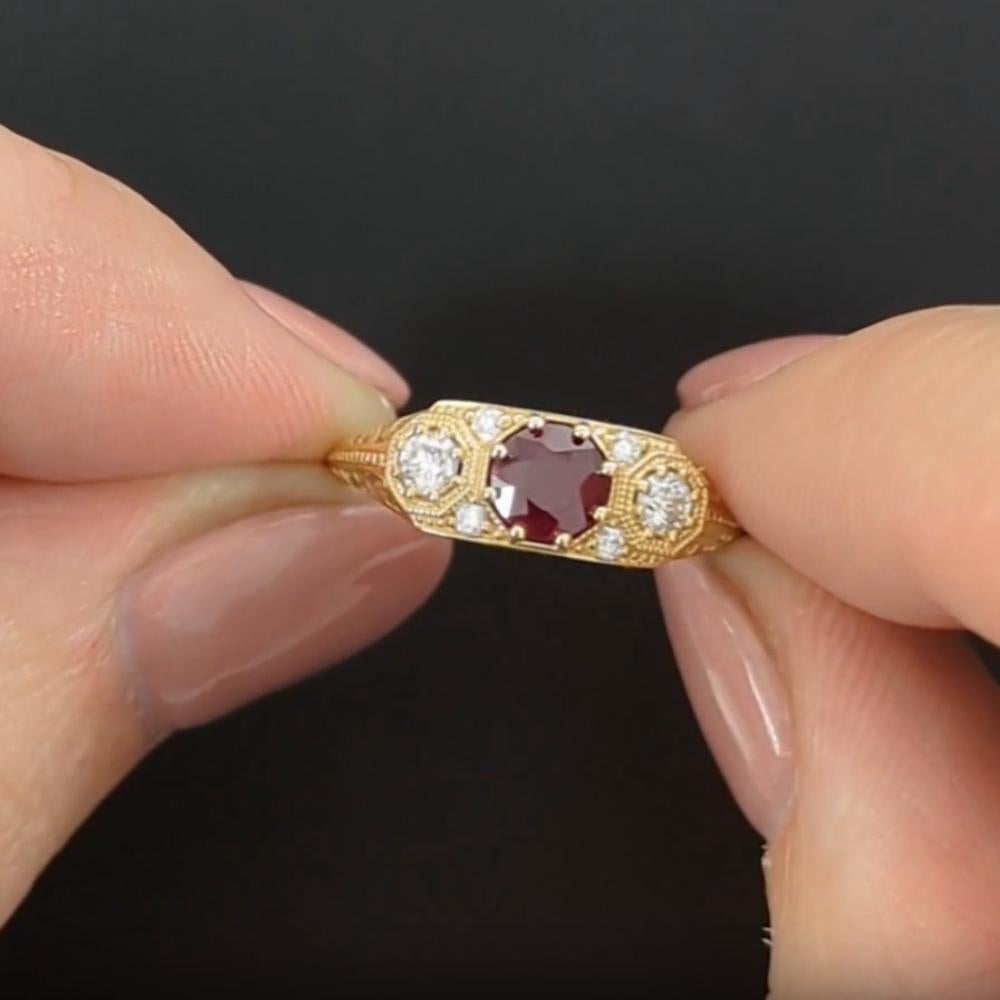 Cette exquise bague à trois pierres de style vintage présente un rubis naturel captivant de 0,72 ct. au centre, flanqué de deux diamants étincelants, le tout élégamment serti dans de l'or jaune. Inspirée de l'époque Art déco, cette bague présente