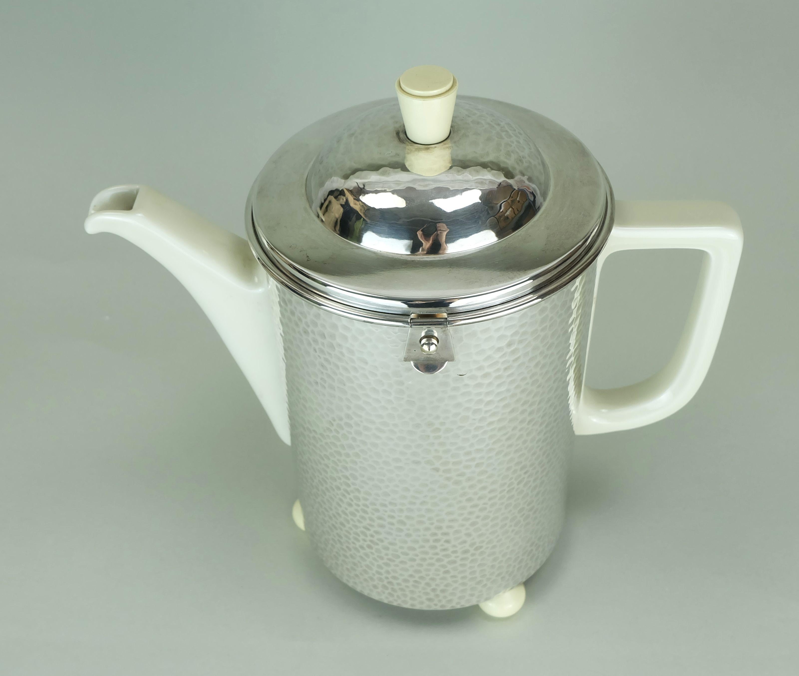 Very beautiful vintage coffee pot from the 1930s. The jug itself is made of white porcelain. The case, lined with felt on the inside, is made of silver plated metal with a hammered surface. Feet and handle are made of light-colored plastic. The jug