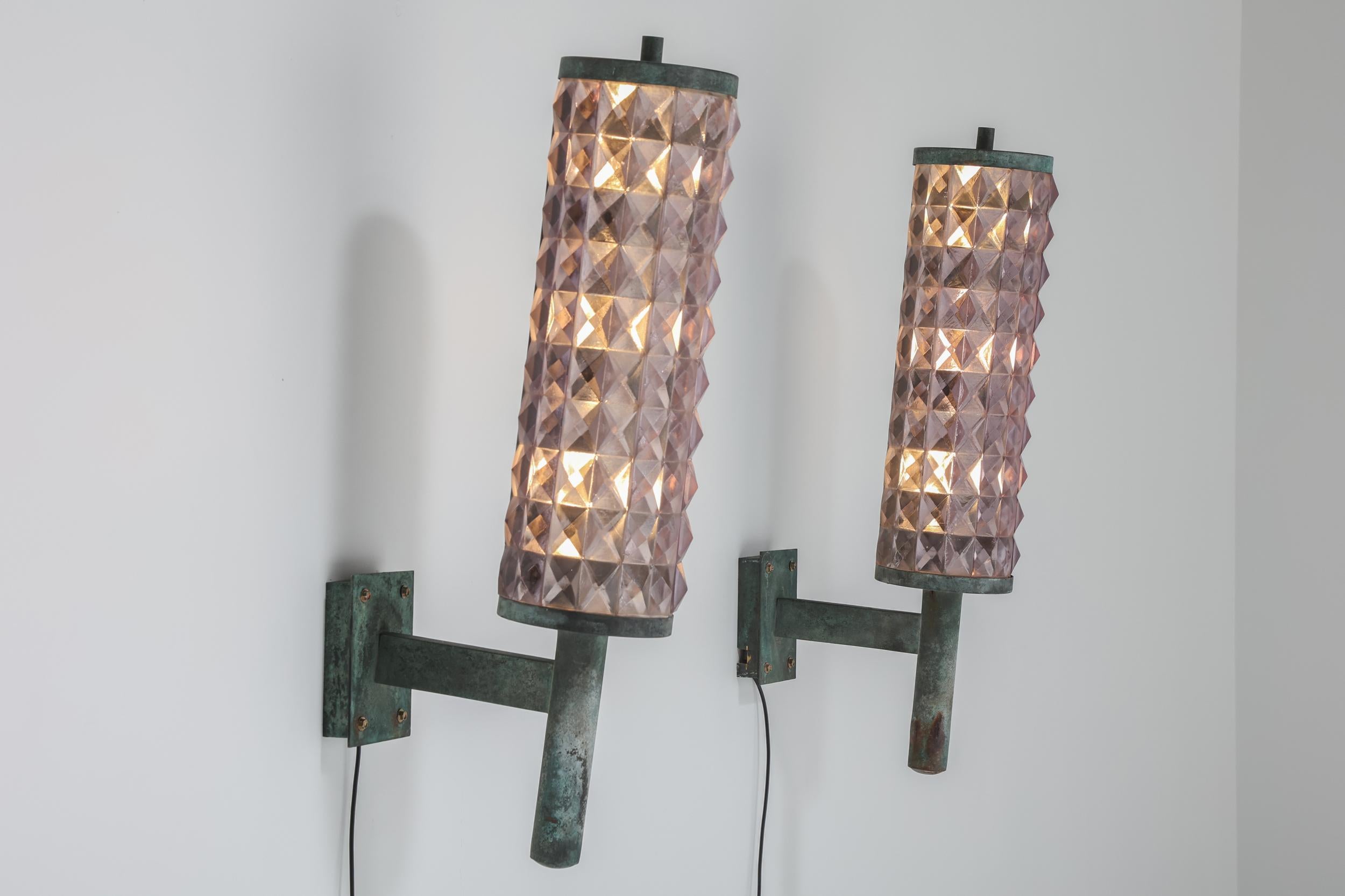 Experience the enduring allure of 1930s French craftsmanship with these Art Deco iron and glass wall sconces. Emitting a captivating warm glow through their tinted glass, these sconces are a remarkable addition to any space. We have two available,