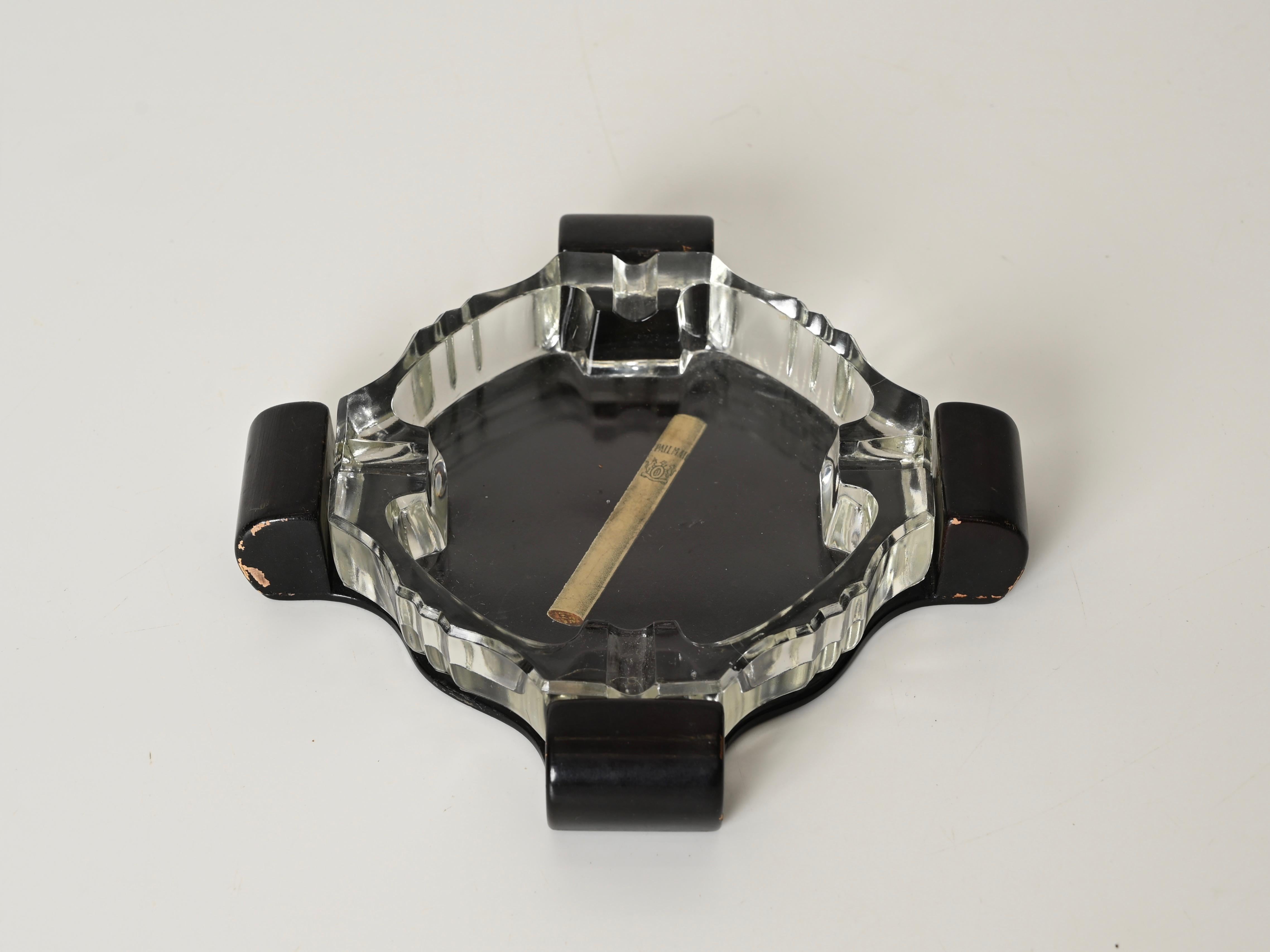Stunning and rare Art Deco Italian ashtray in Crystal and Lacquered Wood. This gorgeous piece was produced in Italy during the 1930s.

Fully original and in amazing condition. This piece features a beautifully faceted crystal tray with a bevelled