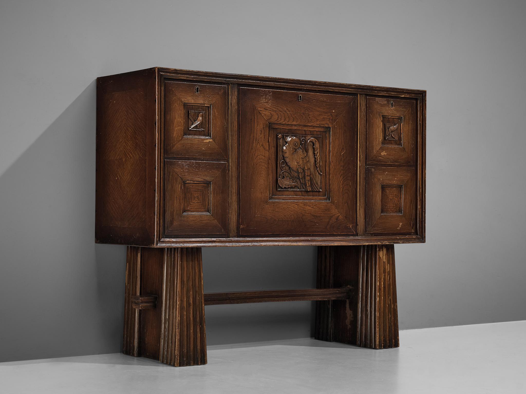 Bar cabinet, stained oak, Italy, 1940s.

Sturdy cabinetin oak with figurative door panels featuring images of birds. The sideboard is equipped with three doors. The middle door holds several drawers which provide plenty of storage space. The two