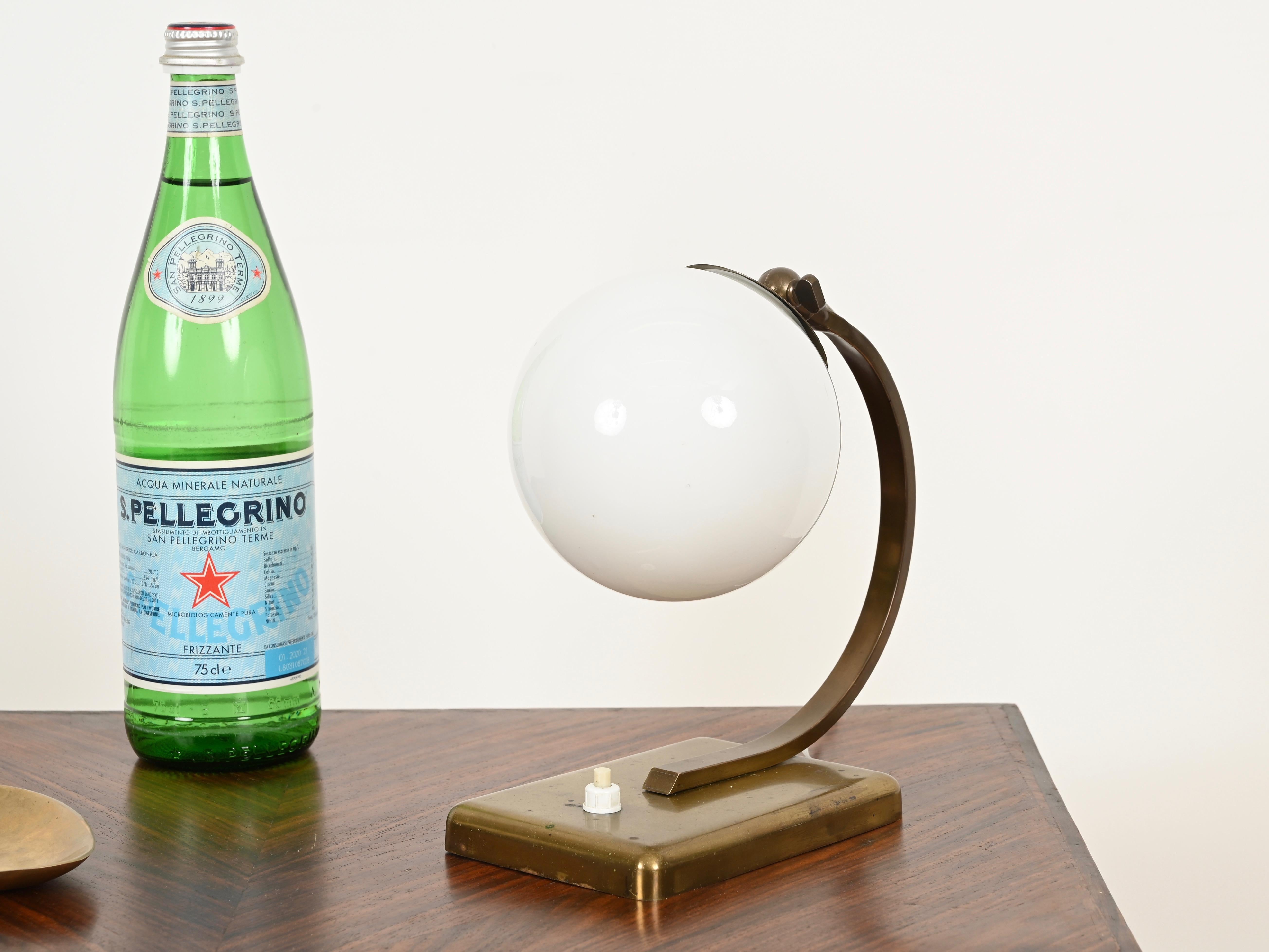 Elegant Italian Art Deco table lamp in solid brass and opaline glass. This refined and rare lamp was crafted in Italy during the 1930s.

In amazing condition, the rich golden patina on the brass has been left unpolished to preserve its charm and