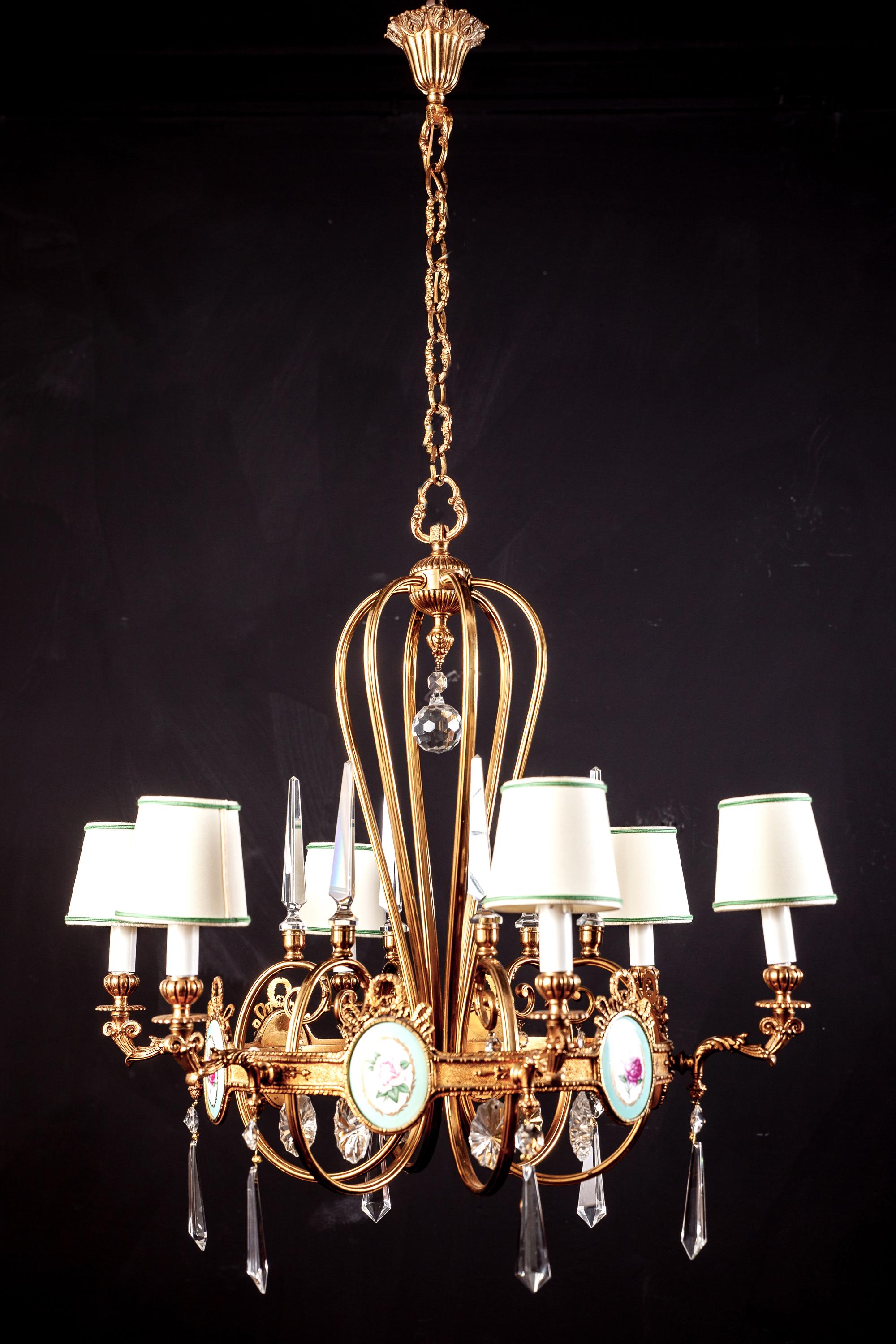 Wonderful six arm Art Deco brass chandelier with fine quality cut crystal pendants adorned with six amazing porcelain plaques decorated with colorful flowers.
Newly rewired six E 14 light bulbs with a white and green rimmed shades.