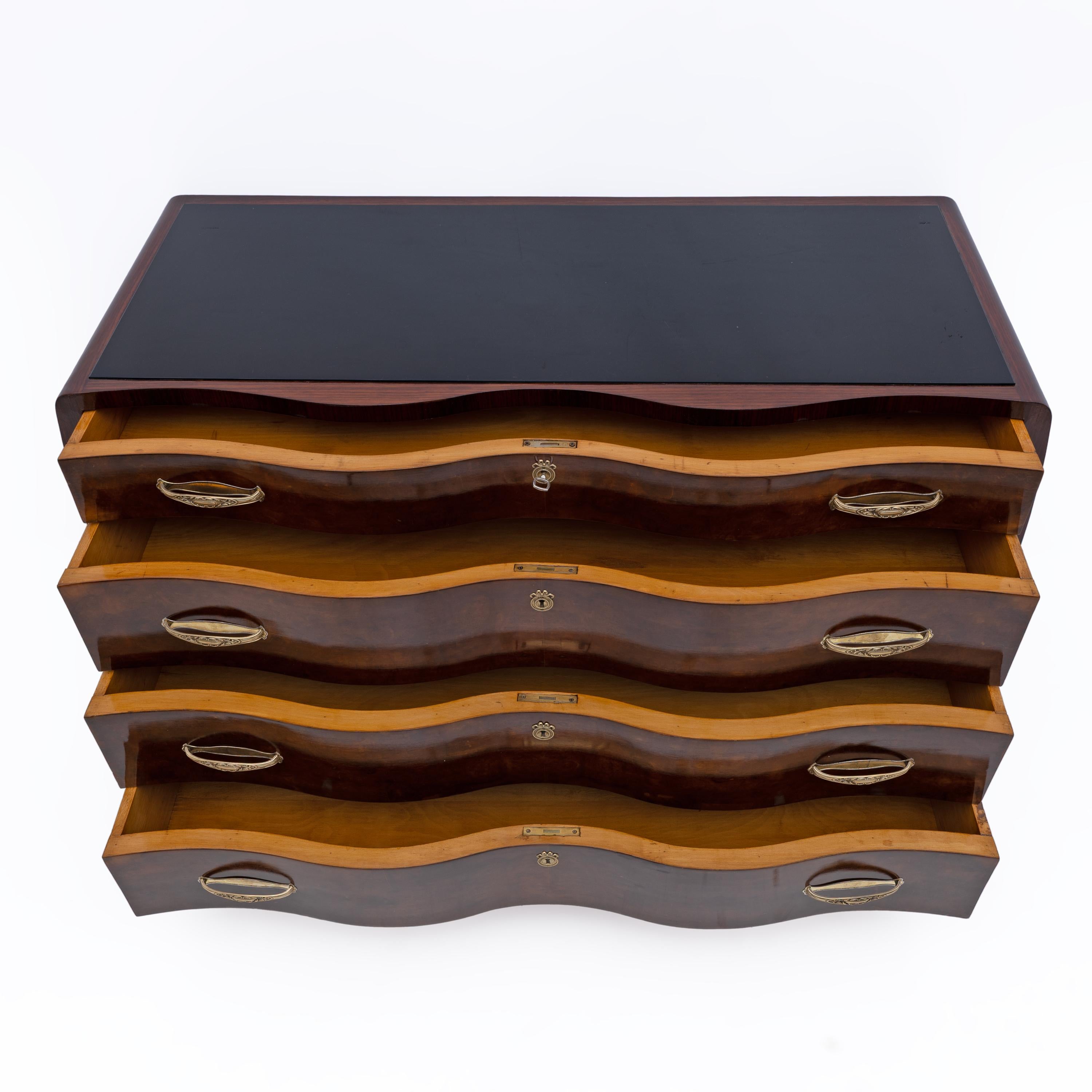Art Deco chest of drawers from the 1930s, containing four drawers with curved central fronts and veneered in Thuja burl, curved sides veneered in Teak and a black glass top. Fully restored and polished with shellac.