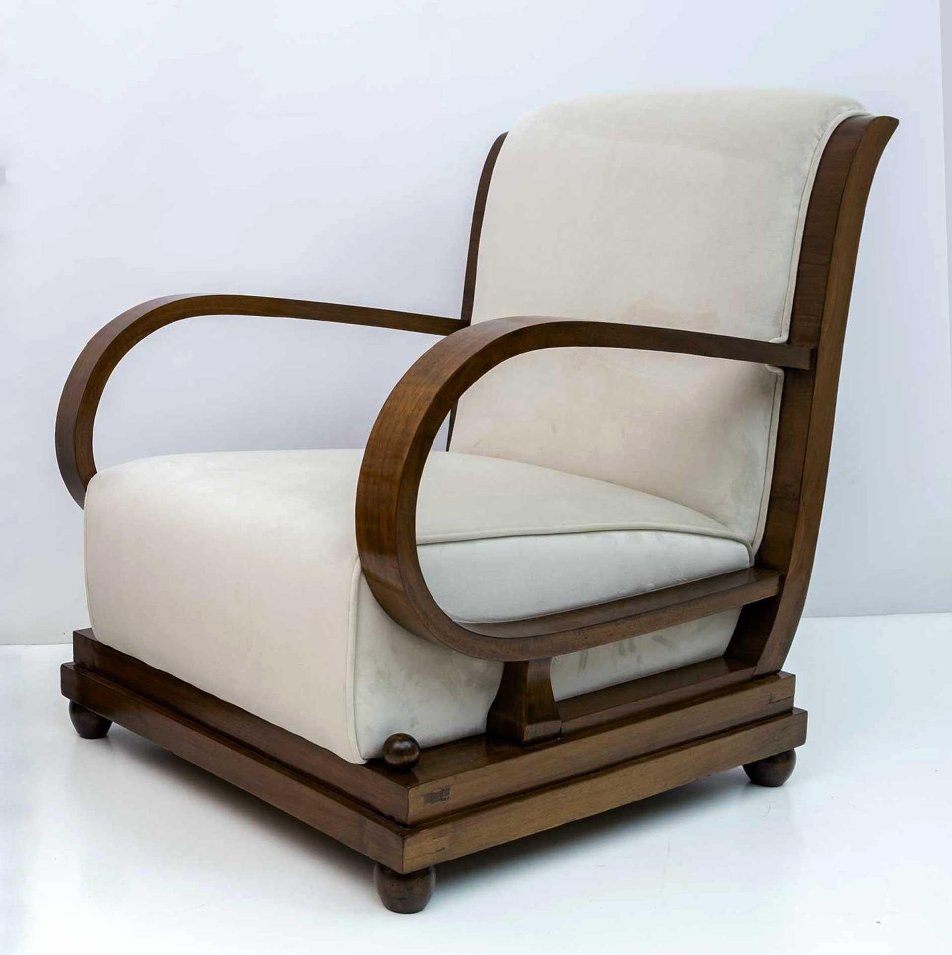Sessel und Ottomane. Der Stuhl aus der frühen Art-déco-Periode in Norditalien ist mit Nussbaumholz und elfenbeinfarbenem Samt gepolstert. Die Rückenlehne ist anmutig geschwungen und verlängert sich, um die Krümmung der abgewinkelten Armlehnen zu