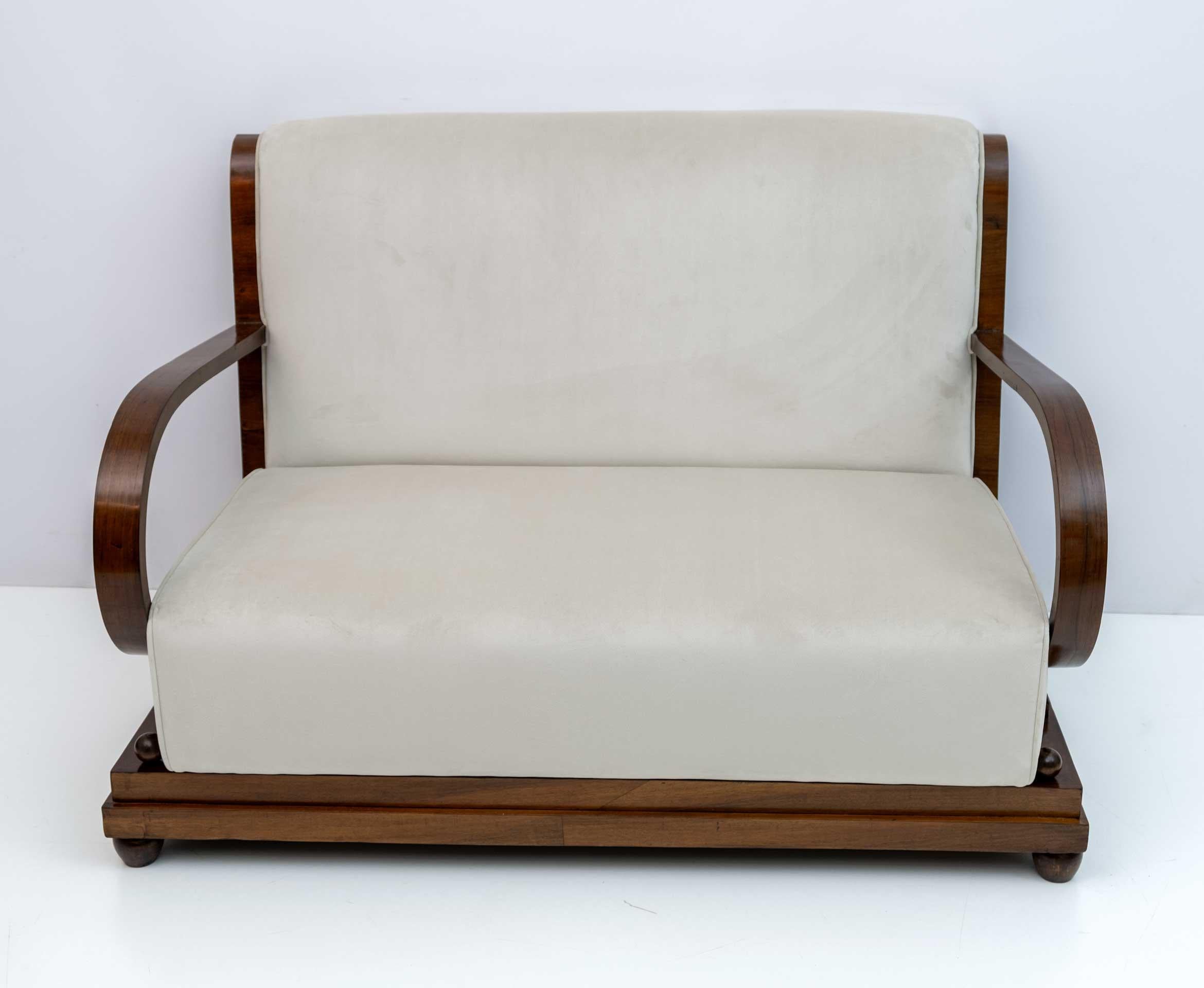 Early Art Deco period Northern Italian sofa, in walnut and ivory velvet upholstery, the back of the sofa is gracefully curved and extends to accentuate the curvature of the sloping armrests. Recently reupholstered and restored with shellac polish. A