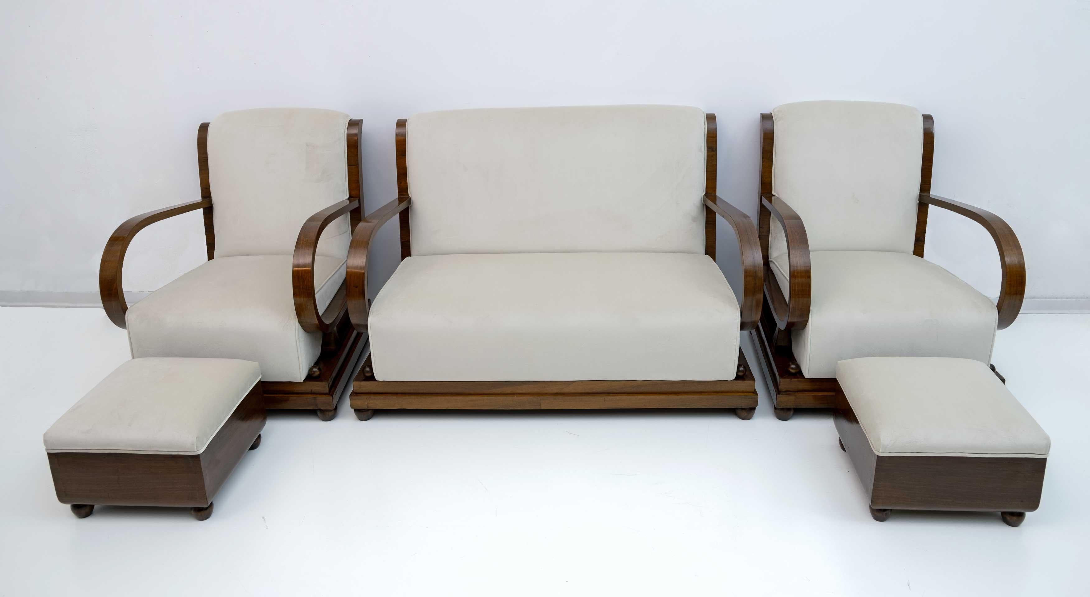 Suite de salon italien des années 1920 comprenant un canapé, une paire de fauteuils et une paire d'ottomans. Datant du début de la période Art Déco en Italie du Nord, en noyer et tapisserie de velours ivoire, les dossiers du canapé et des fauteuils