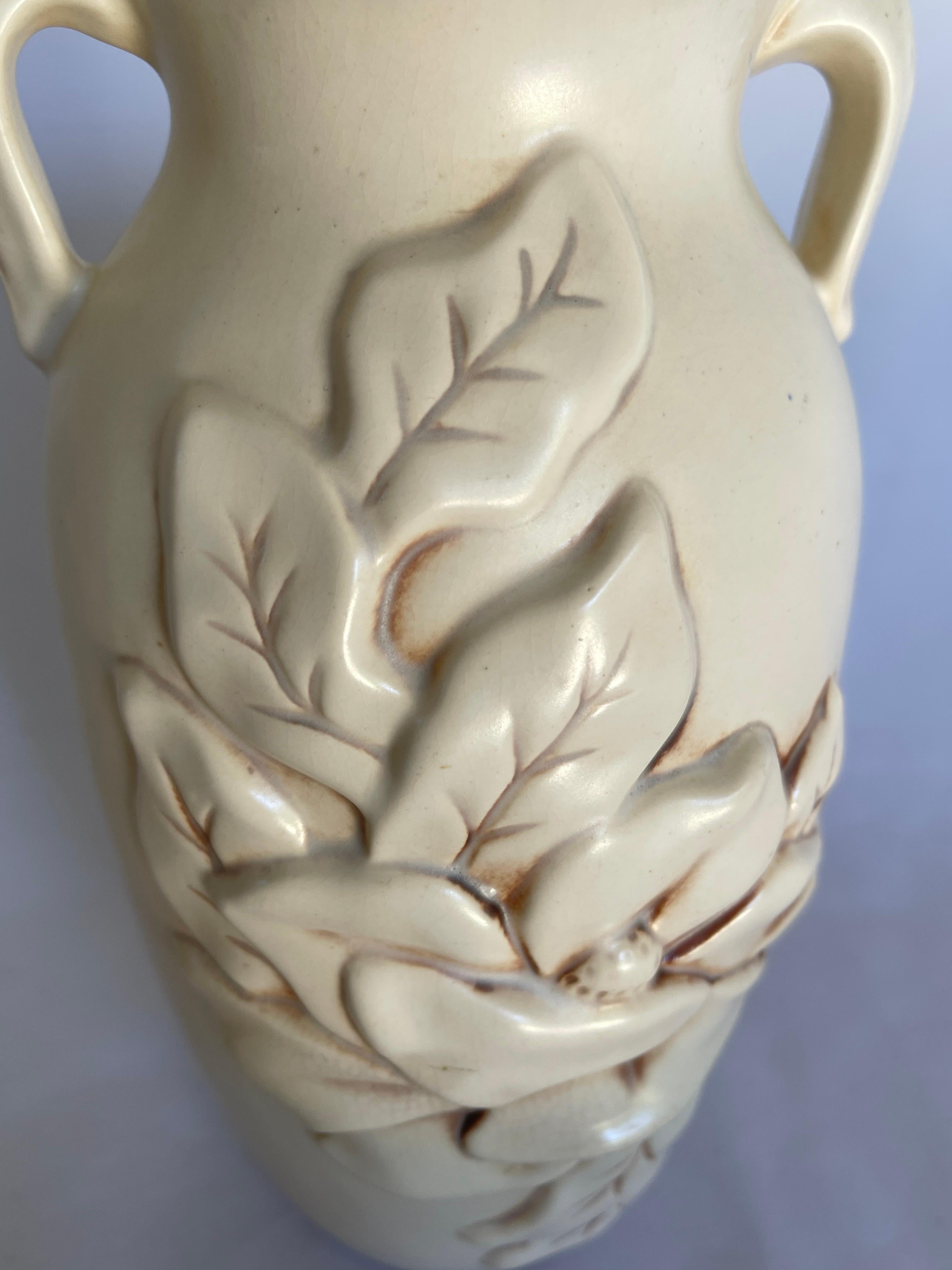 Art Deco ivory pottery vase with double floral design front and double handles with leaf form.  Signed and numbered on bottom,  Red Wing  USA .