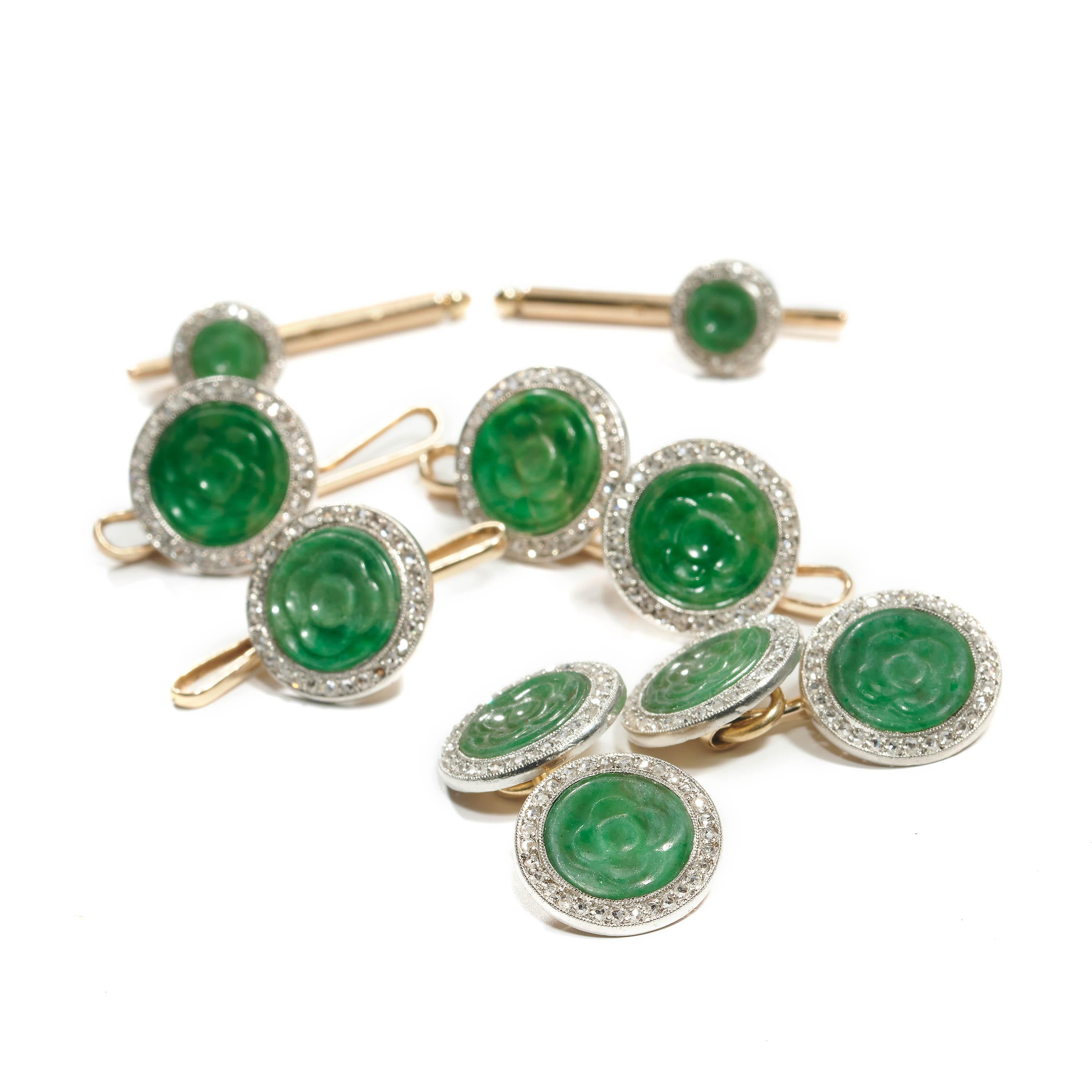 A vintage dress-set comprised of a pair of round cuffinks, four buttons and two collar studs, set with jadeite jade which has been carved to represent a lotus flower, surrounded by a border of old-cut diamonds, mounted in silver and 18ct yellow