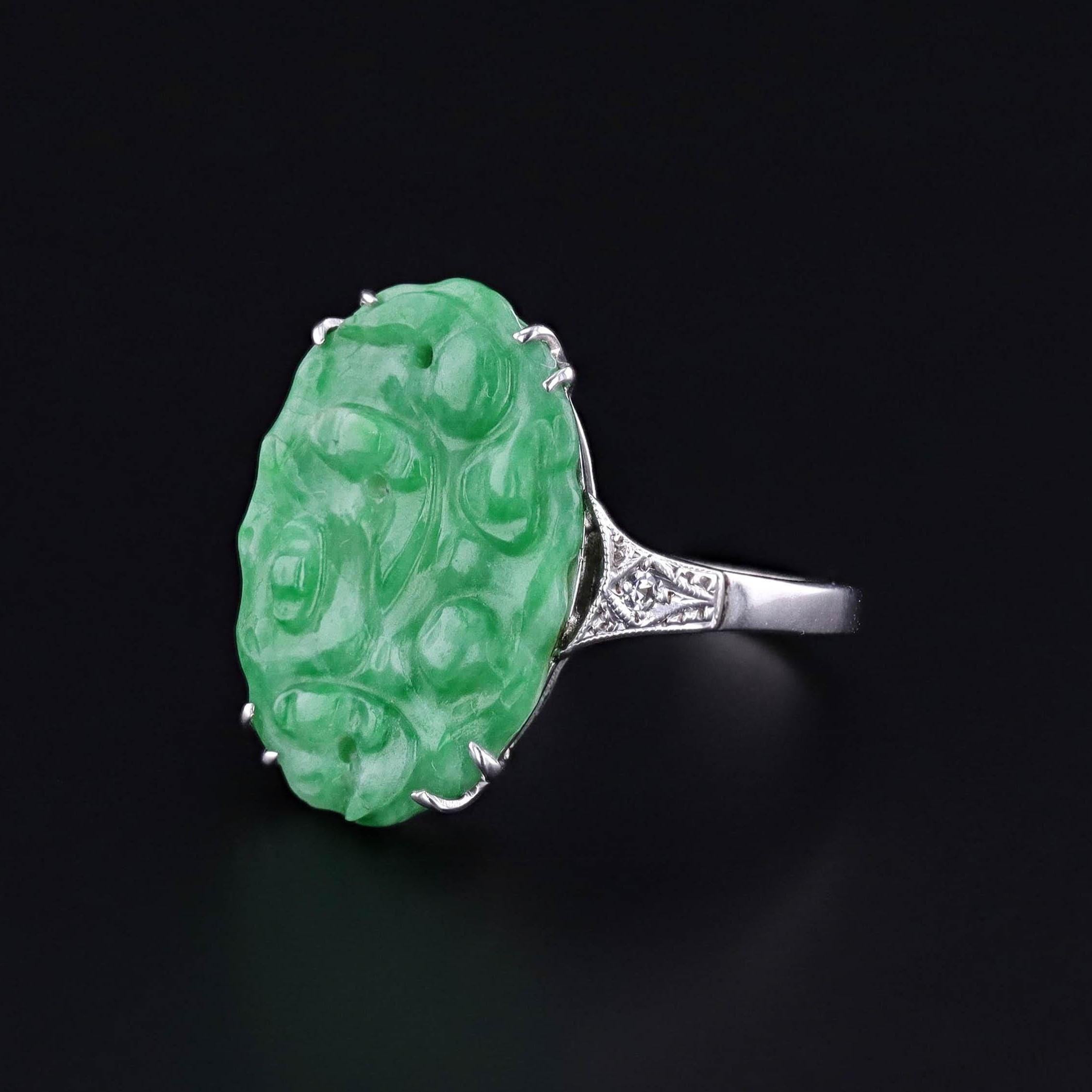 Vintage Jade Ring: This 1930s, Art Deco era ring features a carved jade stone with diamond shoulders set in rhodium plated 9ct white gold.

The face of the ring measures 0.75 inches by 0.5 inches wide and is in great condition. It is a size 7.25 but