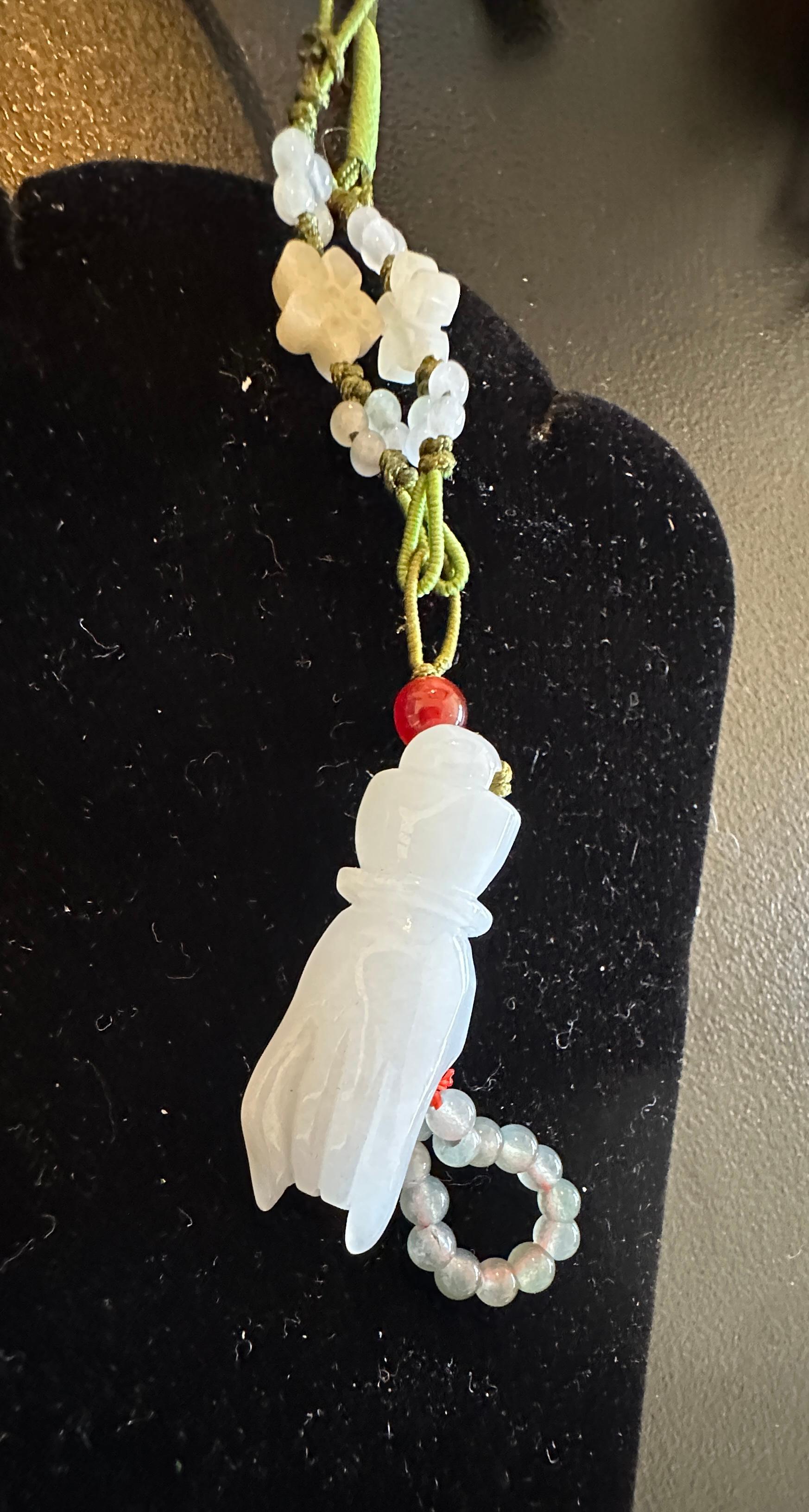 UNA SQUISITA E RARA COLLANA IN GIADA DI MONTONE ART DECO CON UNA MANO SCOLPITA CHE TIENE UN FRUTTO NEL PALMO DELLA MANO E UN FILO DI PERLINE CON FIORI DI GIADA AGGIUNTIVI E UNA PERLA DI CORNIOLA SU UNA COLLANA CINESE DI SETA INTRECCIATA.   LA GIADA