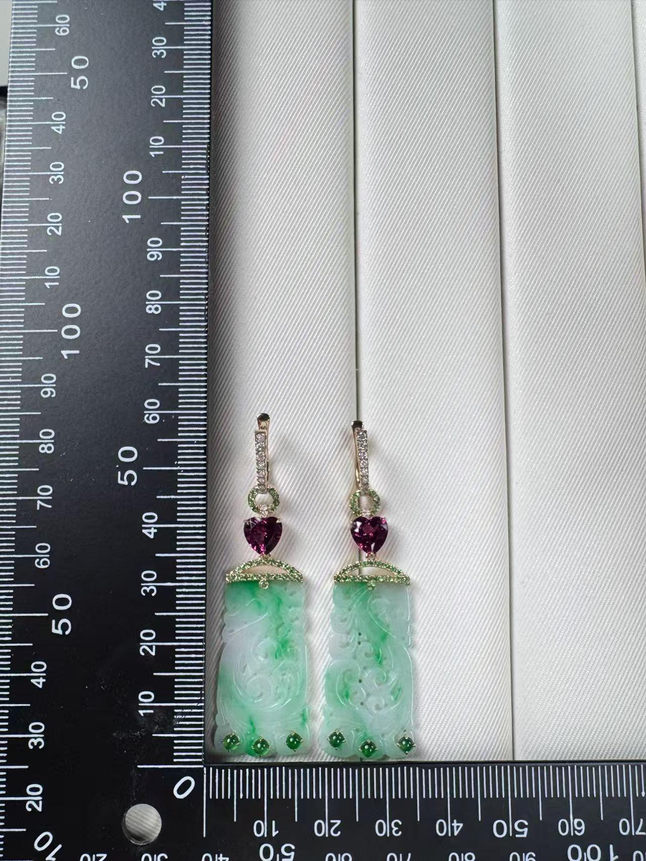 Exquisitamente elaborados en oro amarillo de 14 quilates, estos pendientes presentan una cautivadora fusión de piedras preciosas y arte. En el centro, unos paneles de jade finamente tallados (8,06 ct) muestran delicados motivos calados, símbolo de