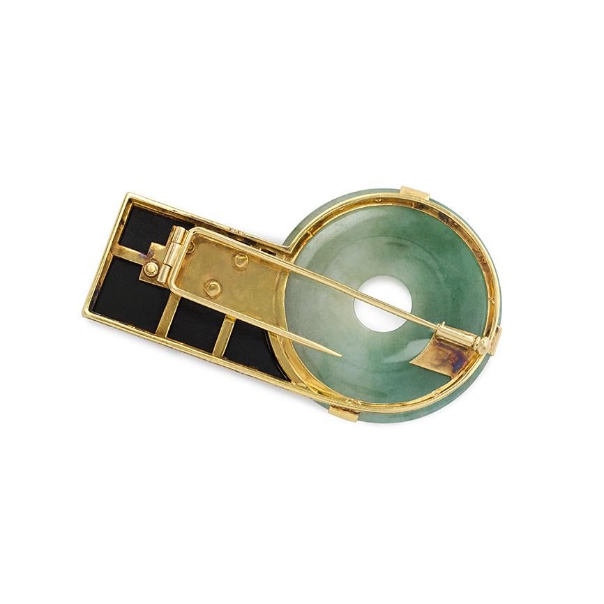An Art Deco brooch of geometric design featuring a jade disk flanked by an onyx segment and surmounted by diamond and platinum bars, in 18k gold. Atw. 1.25 ct. diamonds. Austrian import