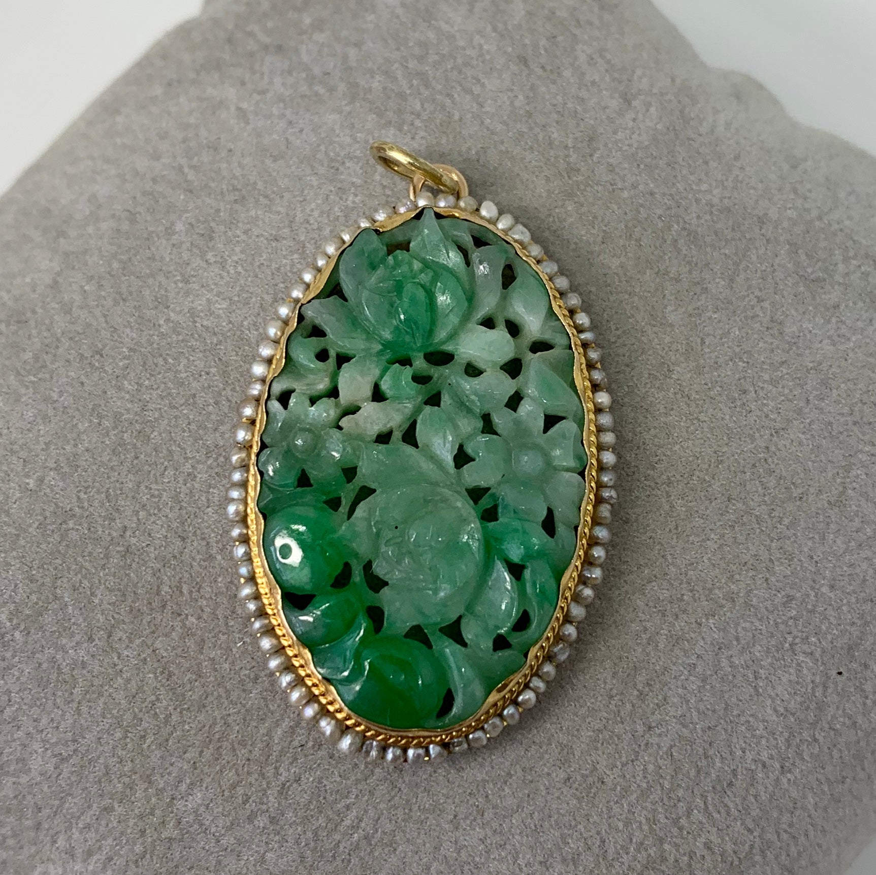 THIS IS A VERY BEAUTIFUL ORIGINAL ART NOUVEAU - ART DECO PENDANT WITH A STUNNING CARVED JADE MEDALLION OF GREAT BEAUTY SURROUNDED BY A DECORATED 14 KARAT GOLD BORDER WITH A HALO OF SEED PEARLS.   THE OVAL JADE IS CARVED WITH A FLOWER MOTIF WHICH I