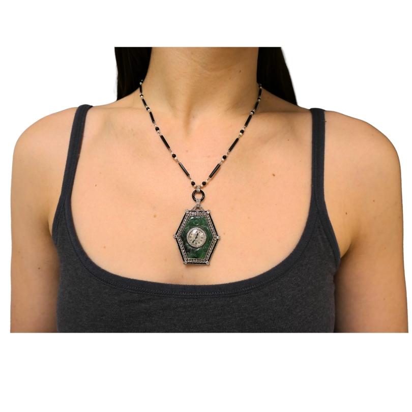 A striking Art Deco Jaeger-LeCoultre watch pendant, crafted of platinum, jade, diamonds and black onyx, on a platinum, seed pearl and black onyx chain necklace.
The elongated hexagonal shape case is made of platinum. It’s centered by the diamond-set