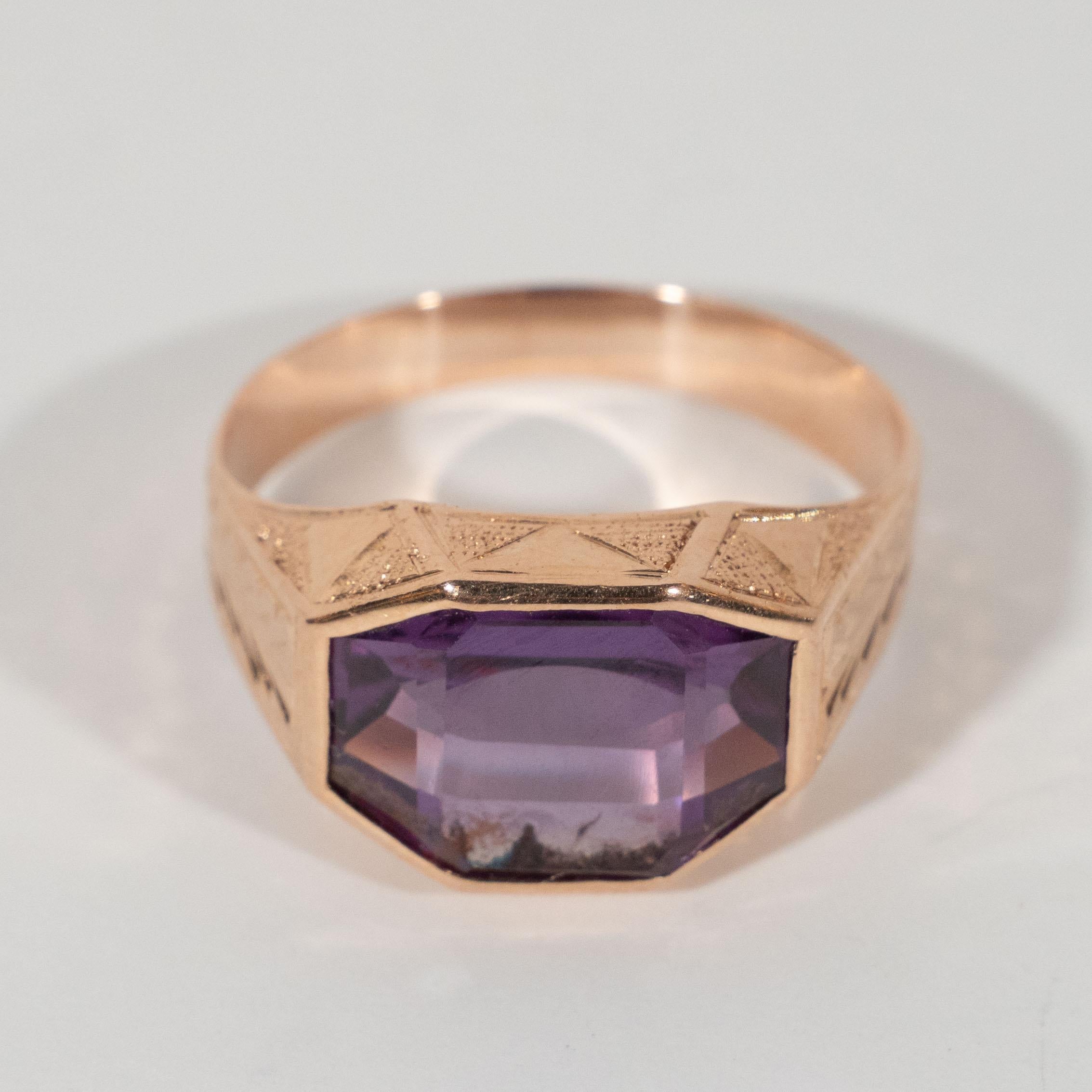 This stunning and glamorous Art Deco 14kt rose gold and amethyst ring was hand crafted in the United States circa 1925. It features an octagonal cut amethyst set in 14kt rose gold with stylized foliate detailing on the shoulders and geometric