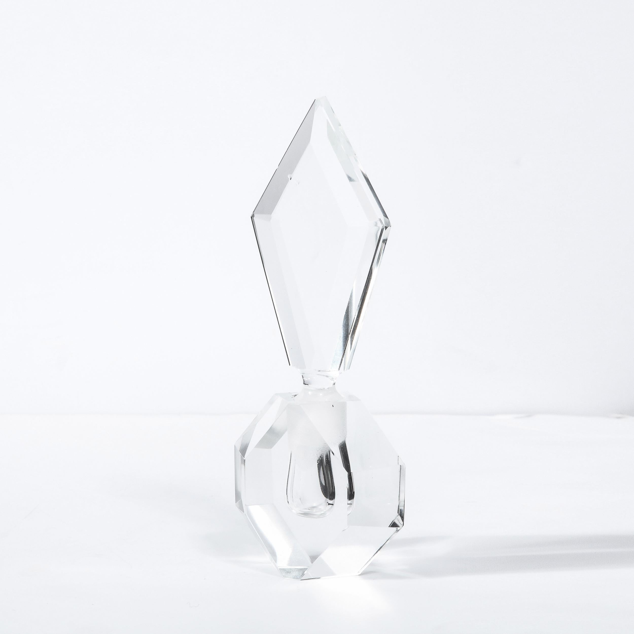 This elegant Art Deco perfume bottle was realized in the United States circa 1935. It features a prismatic geometric form of cut translucent crystal- resembling a small diamond. It is fitted with an elongated rhombus form stopper also in cut crystal