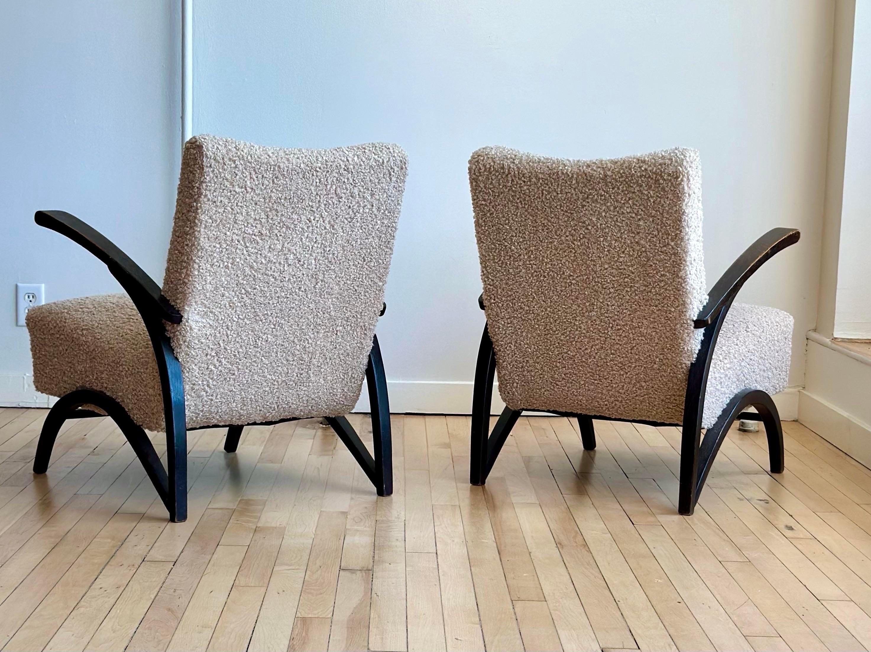 Striking pair of Art Deco period arm chairs designed by Jindrich Halabala for Thonet circa 1930. Gorgeous sleek wooden frames in their original black finish contrast with the new upholstery in a rich boucle.