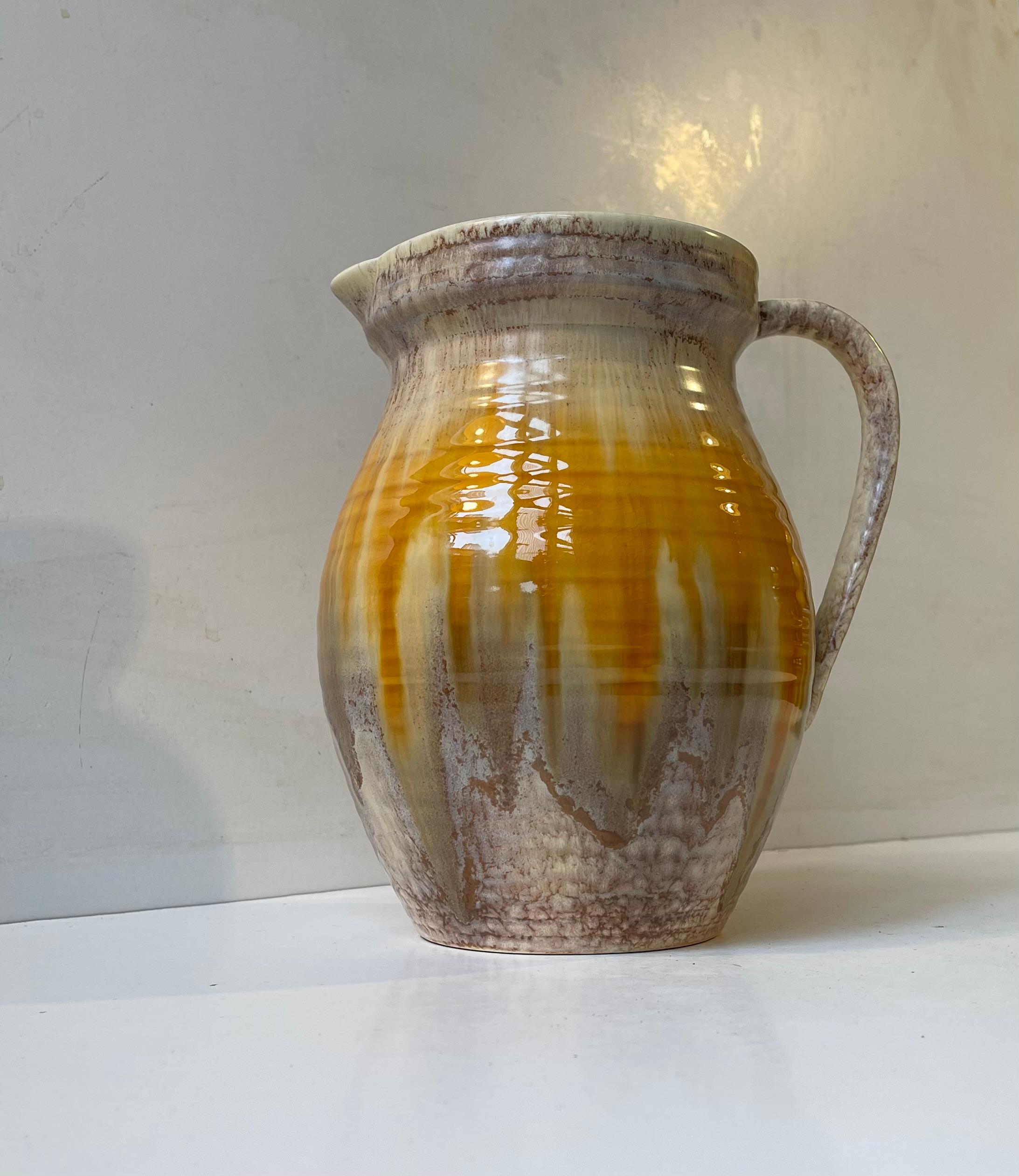 Une étonnante cruche en poterie presque monumentale provenant de Sylvac, en Angleterre. Ce Design/One 1410 date des années 1930 et présente des glaçures brunes et jaunes délicates à la texture osseuse. Une belle pièce ornementale pour les intérieurs