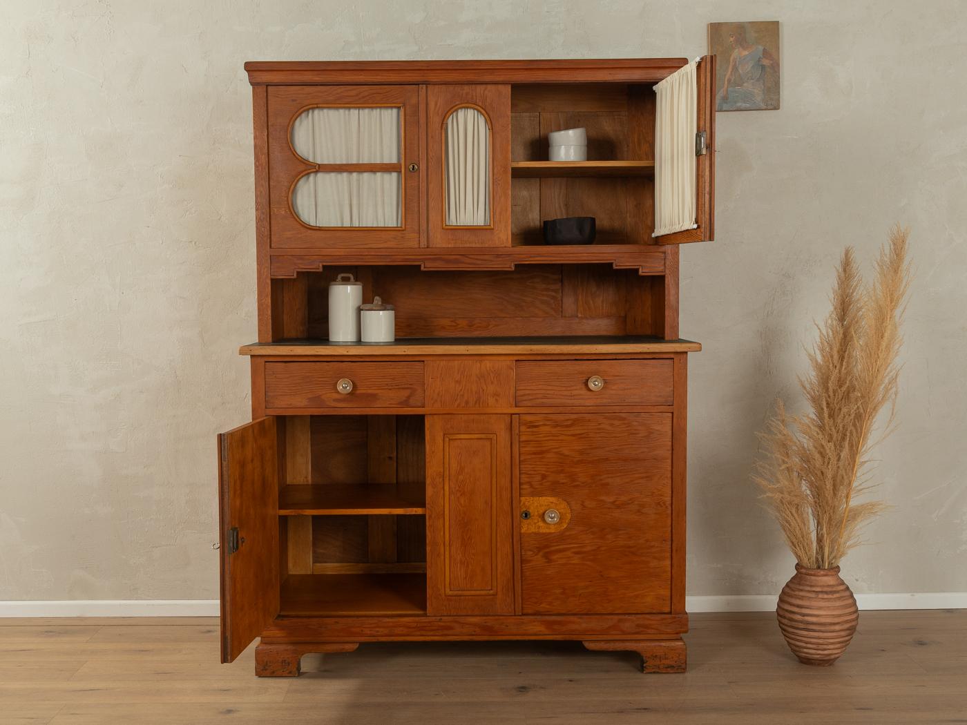 Mobile da cucina Art déco degli anni '20. Corpo di alta qualità realizzato in listellare impiallacciato frassino con due ante, due ante in vetro, due cassetti in legno massiccio, due ripiani, tende nuove e piedini tipici dell'epoca. Progettato e