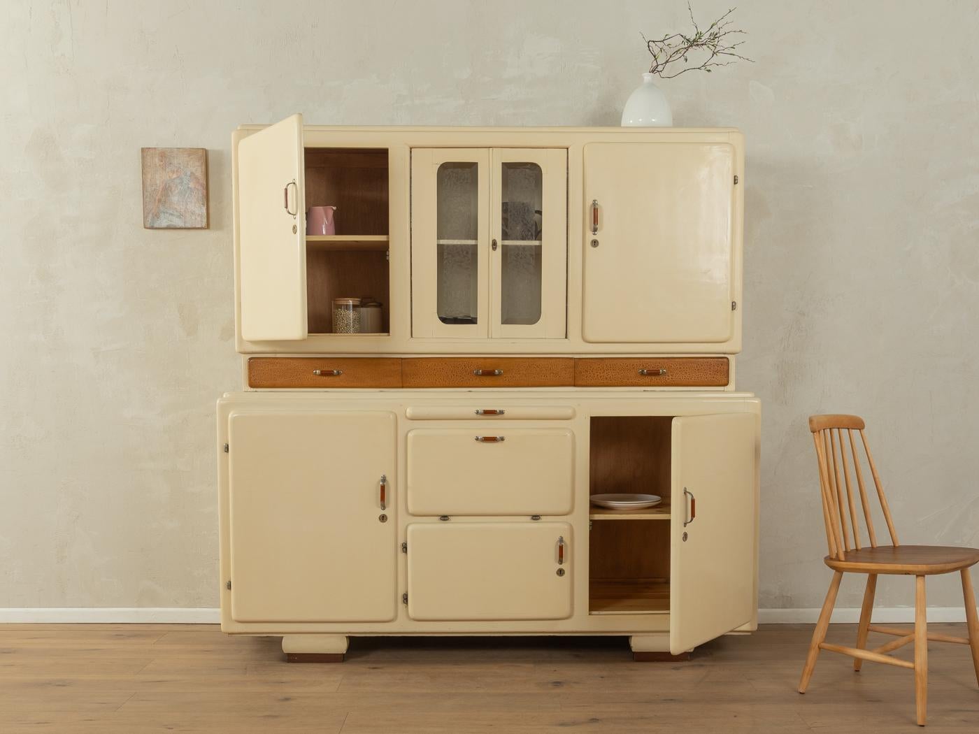 Wonderful two-piece Art Deco kitchen cabinet from the 1930s. High-quality corpus made of wooden panels with ten doors, four shelves, one pull-out, four drawers and ten glass jars. Designed and manufactured in Germany.

The interior of the kitchen