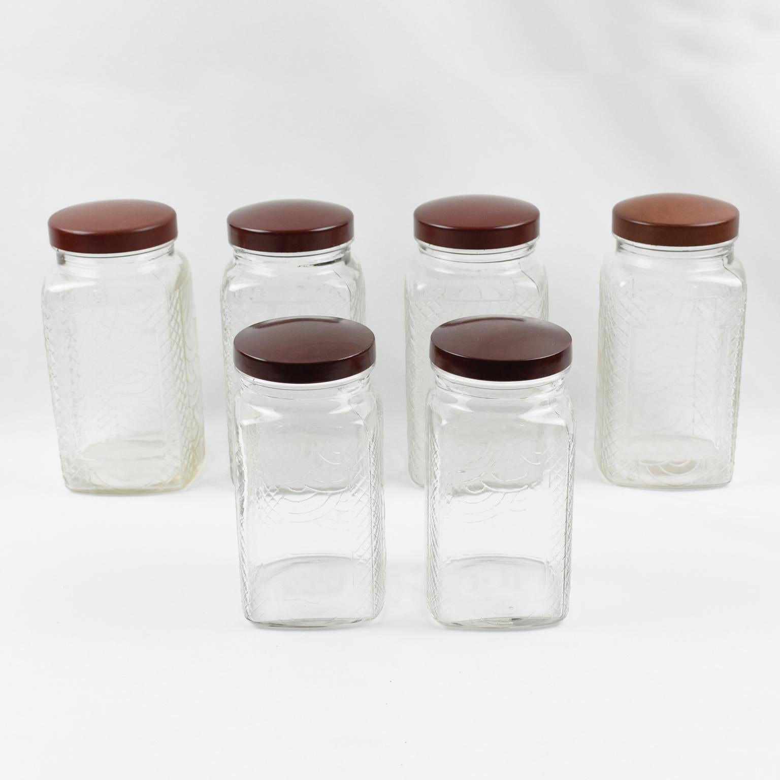 These stunning French Art Deco kitchen canister jars, six pieces in assorted sizes, were crafted in the 1930s. Two sizes are available in this set: large and medium. The containers have a geometric square shape. The molded glass has a typical Art
