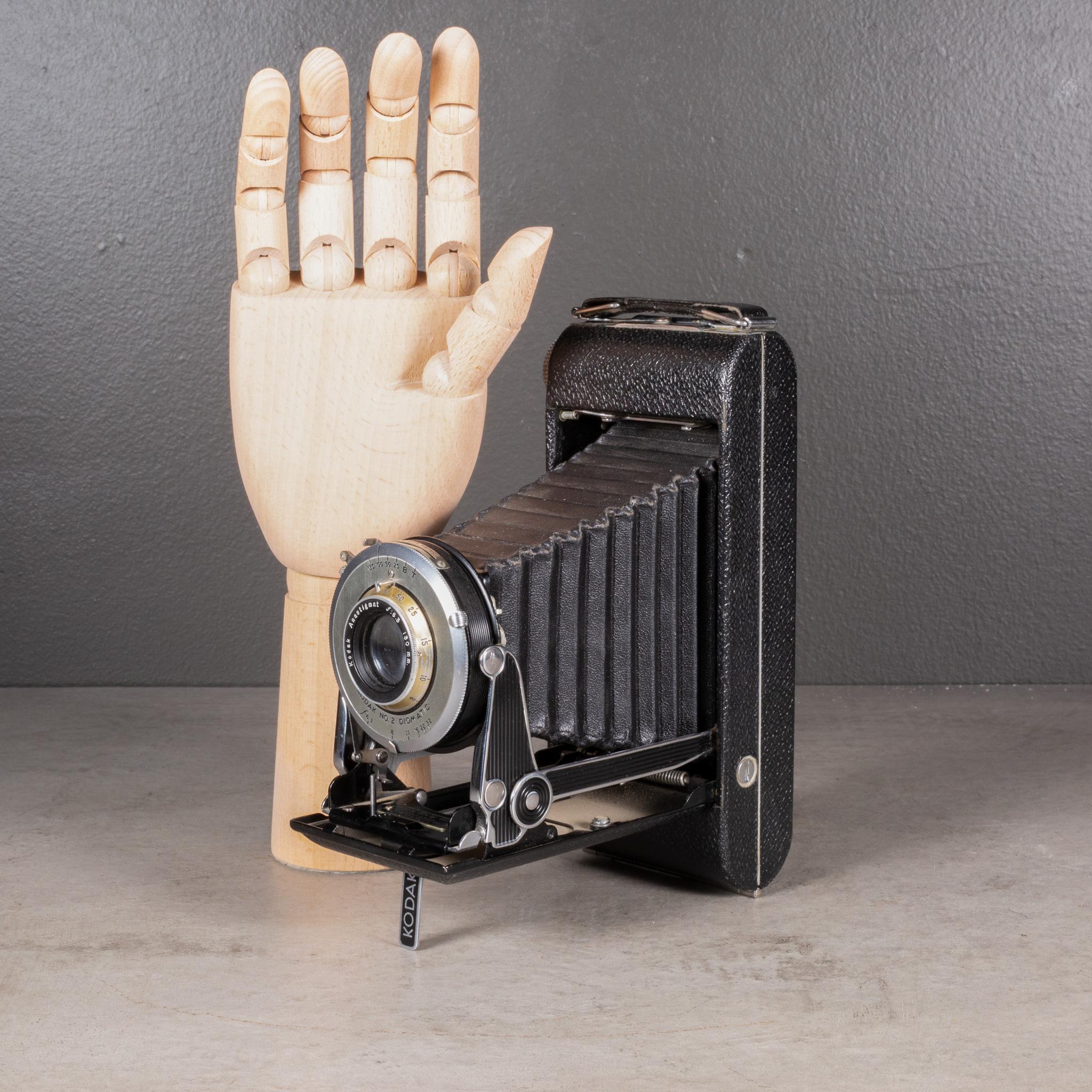 À PROPOS DE

Appareil photo pliant Kodak Senior Six-16 de style Art déco, avec un boîtier enveloppé de cuir, des accents chromés et noirs et un viseur escamotable.

Représenté avec une main grandeur nature. Vendu uniquement à titre décoratif. Peut