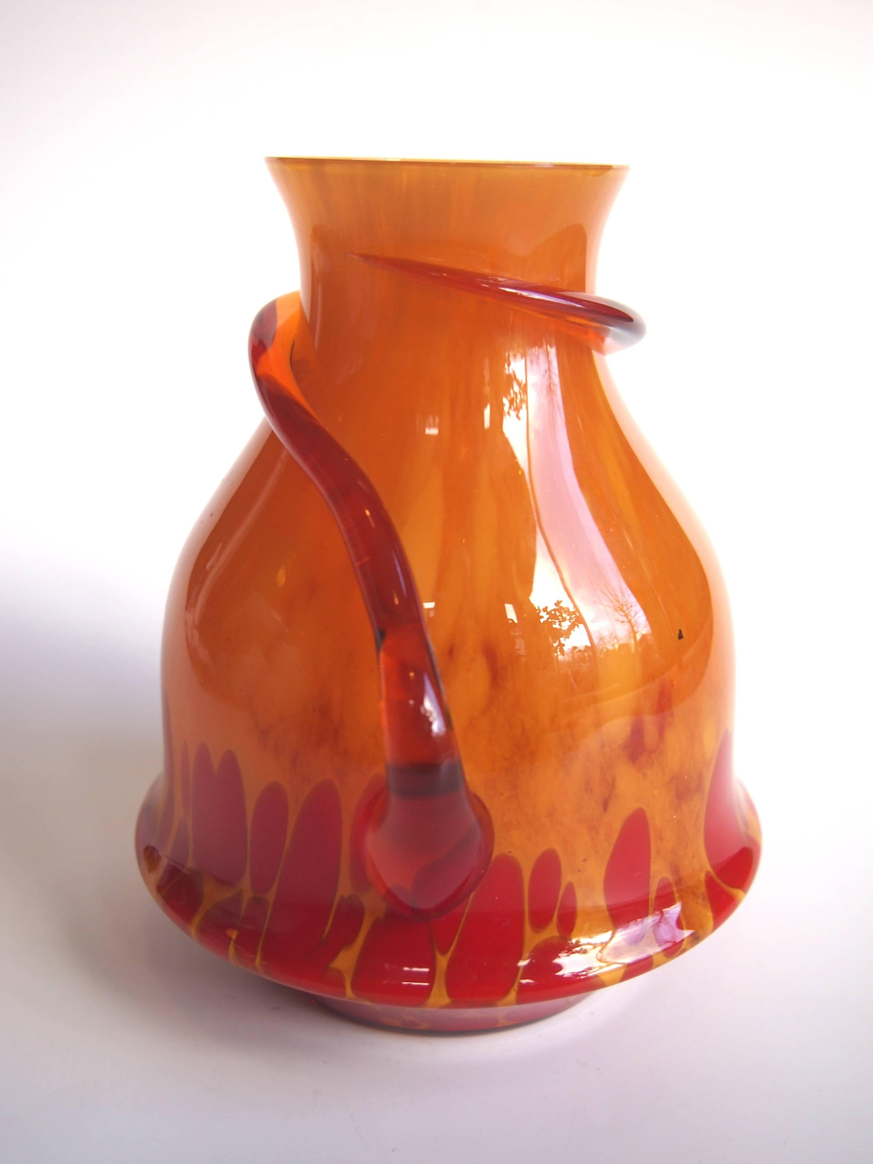 Unusual red over cased amber Kralik vase with hot applied handles wrapped around the vase.

Kralik was at the time one of the largest Bohemian glass makers only a few miles down the road from Loetz. Along with their brother company (Meyr's Neffe)
