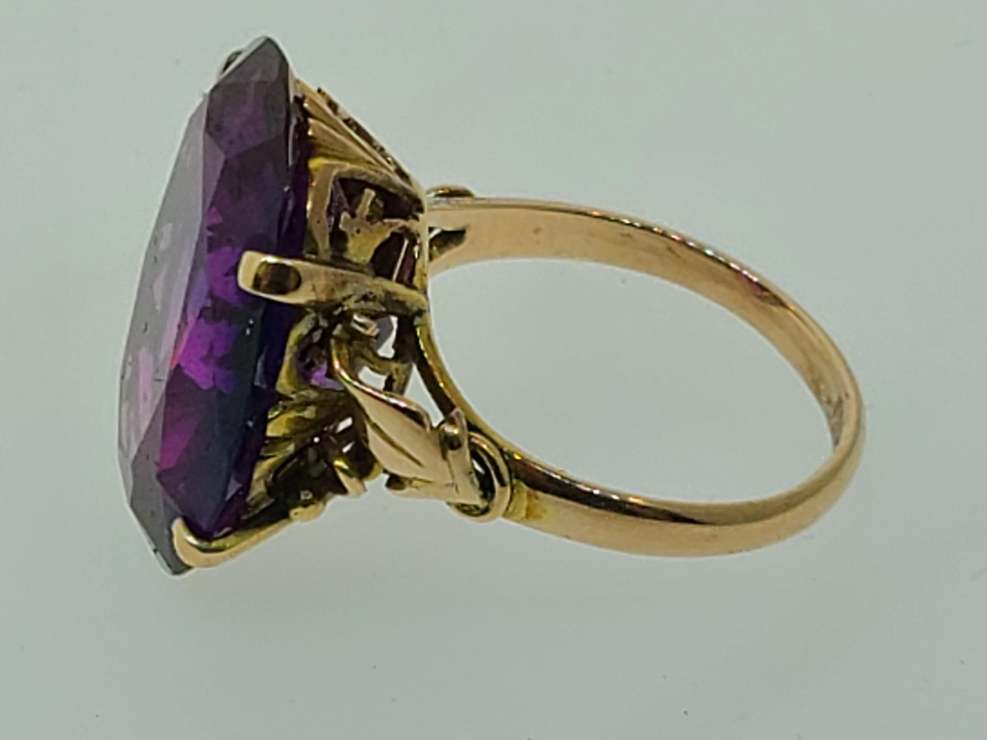 This gorgeous Art Deco era cocktail ring, circa 1930s, is crafted beautifully in a soft hue of 14K yellow gold. With a bold and beautiful, 20mm x 16mm, oval cut lab created Alexandrite as the centerpiece of this stunning ring is approximately 20ct