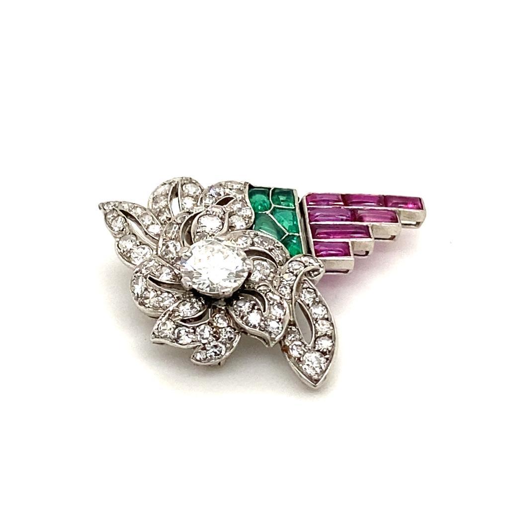 An Art Deco LaCloche platinum, diamond, ruby and emerald brooch.

This exceptional brooch is set with a principal transitional cut diamond measuring 0.85 carat approximately assessed as I-J colour, VS2-SI1 approximately. With additional single cuts